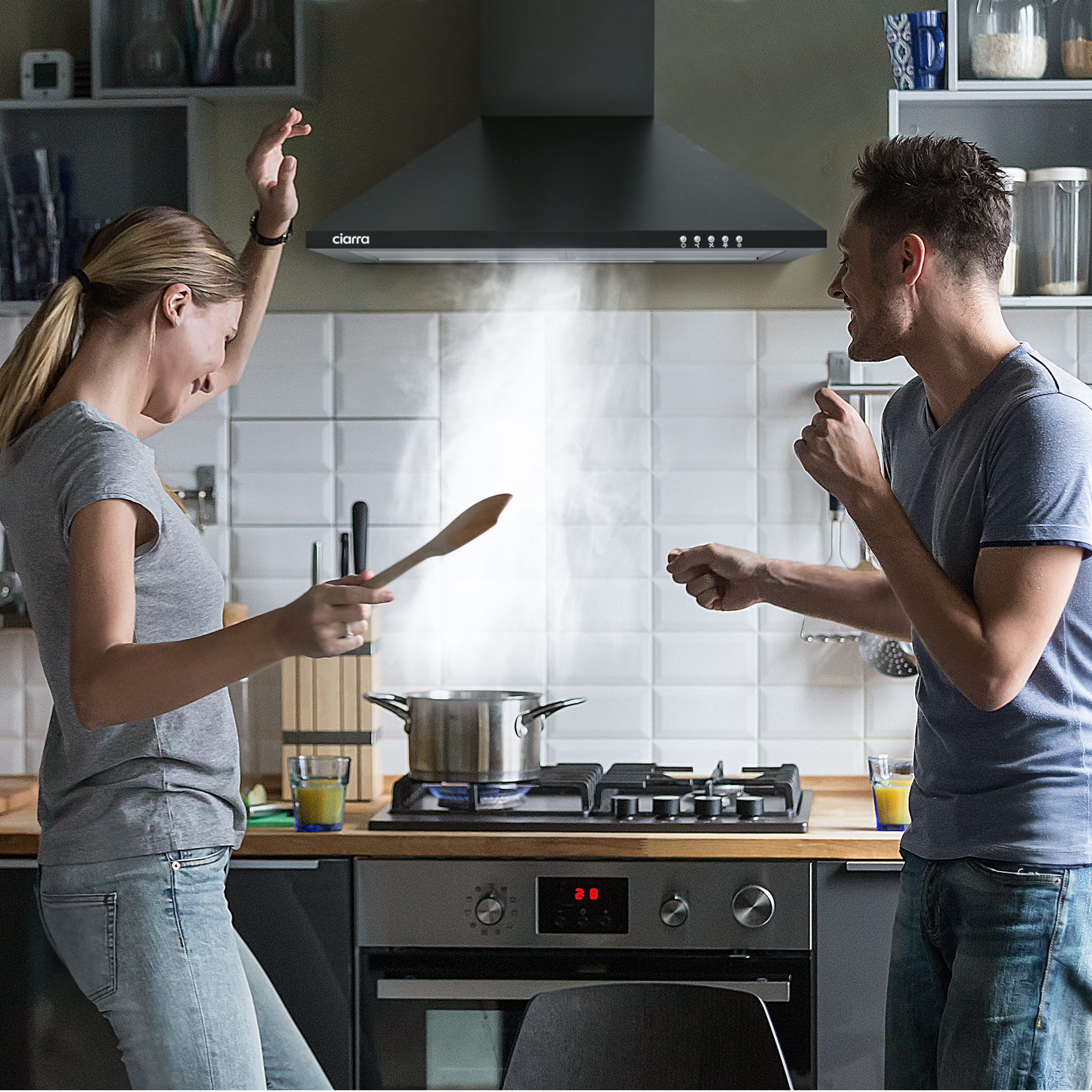 Koppel danst in de keuken met koken. Vrouw houdt houten lepel vast, man danst. Stoom uit pan.