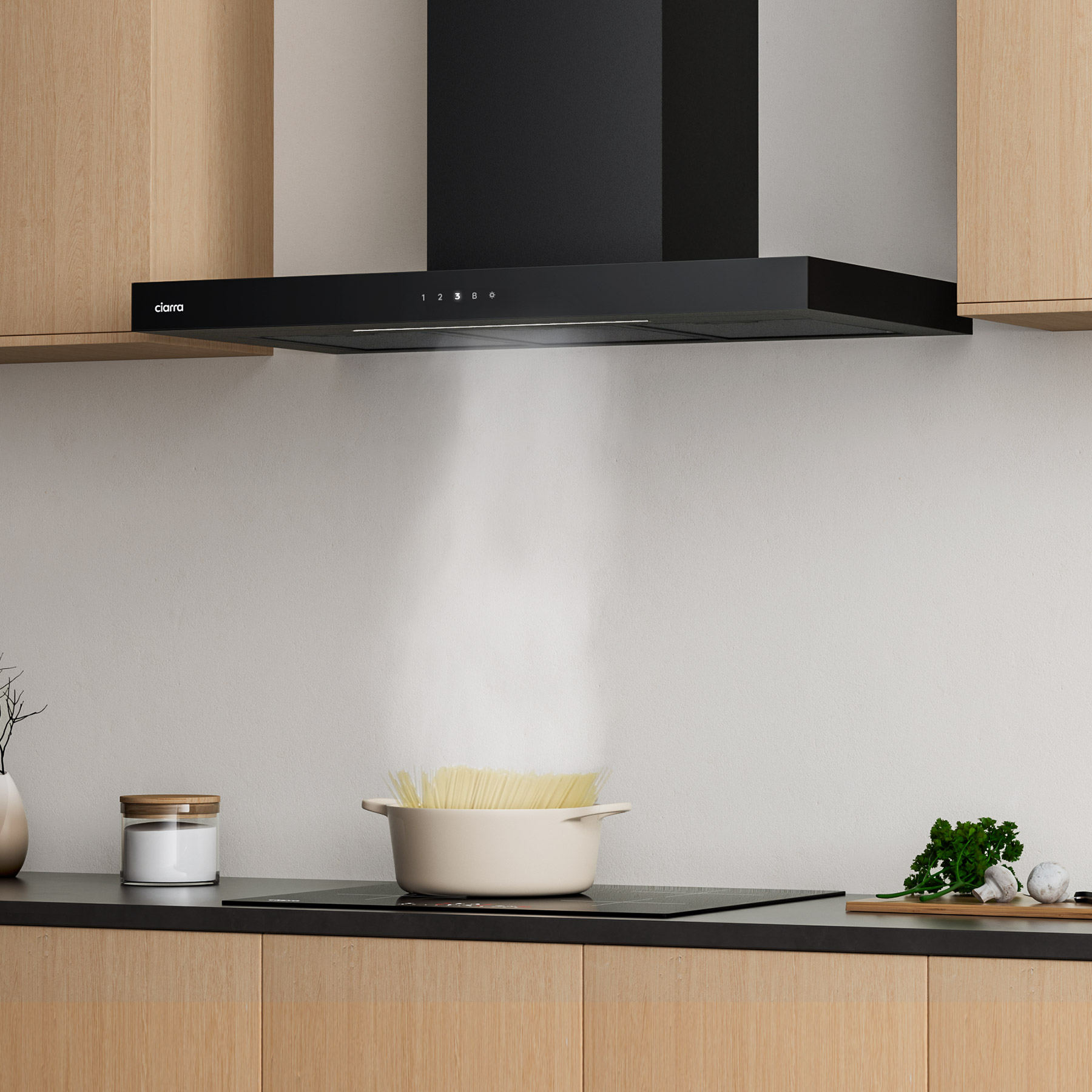 Escena de cocina con una campana extractora negra sobre una estufa con una olla de pasta.