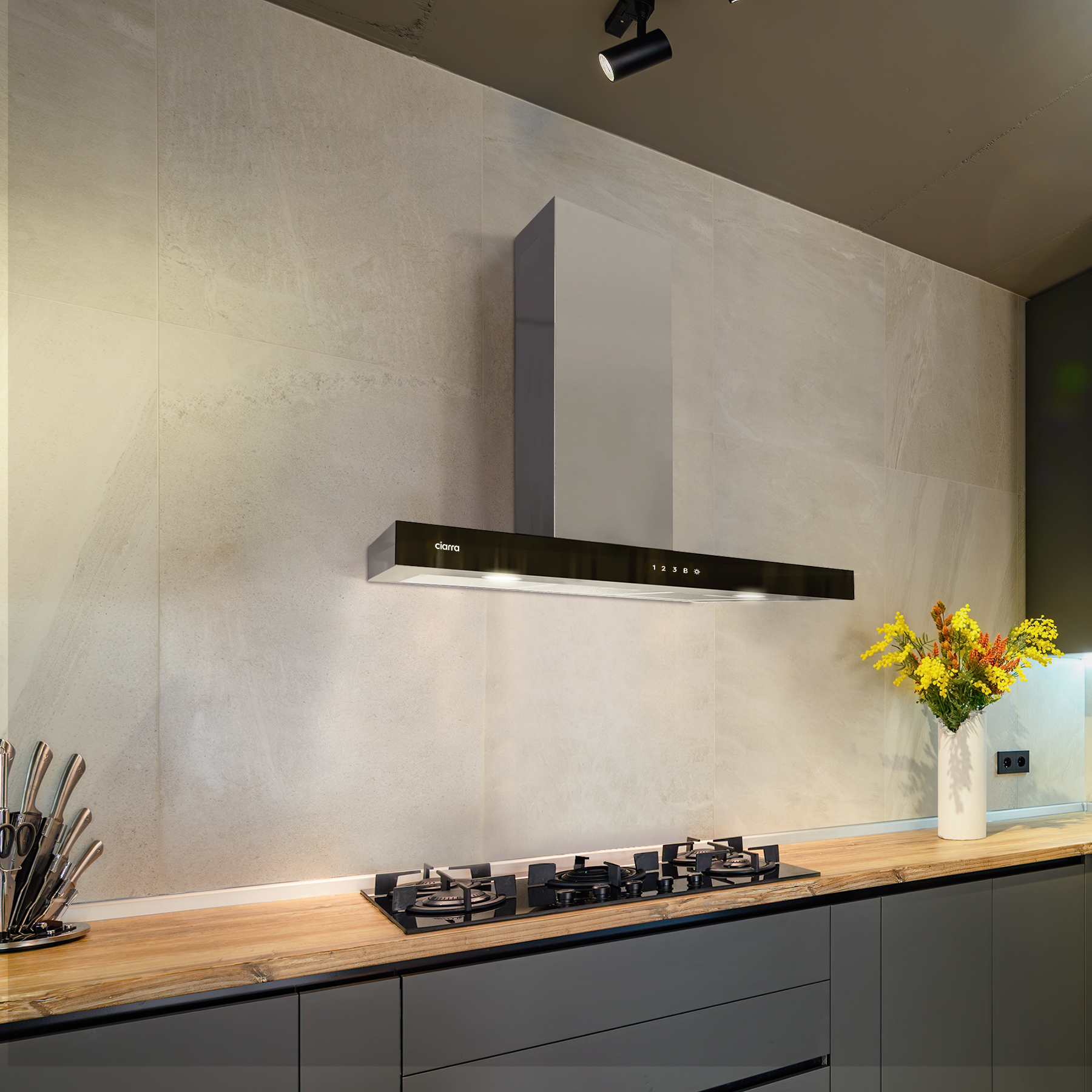 Scena cucina moderna con cappa, piano cottura e bancone. Parete beige.