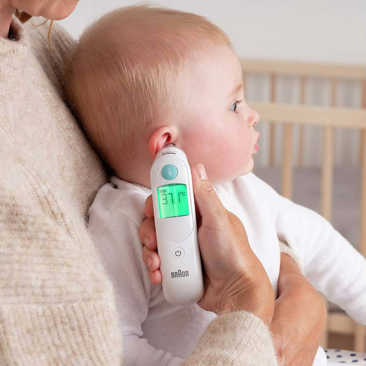 L'orecchio del bambino viene controllato con un termometro auricolare. Sfondo bianco.