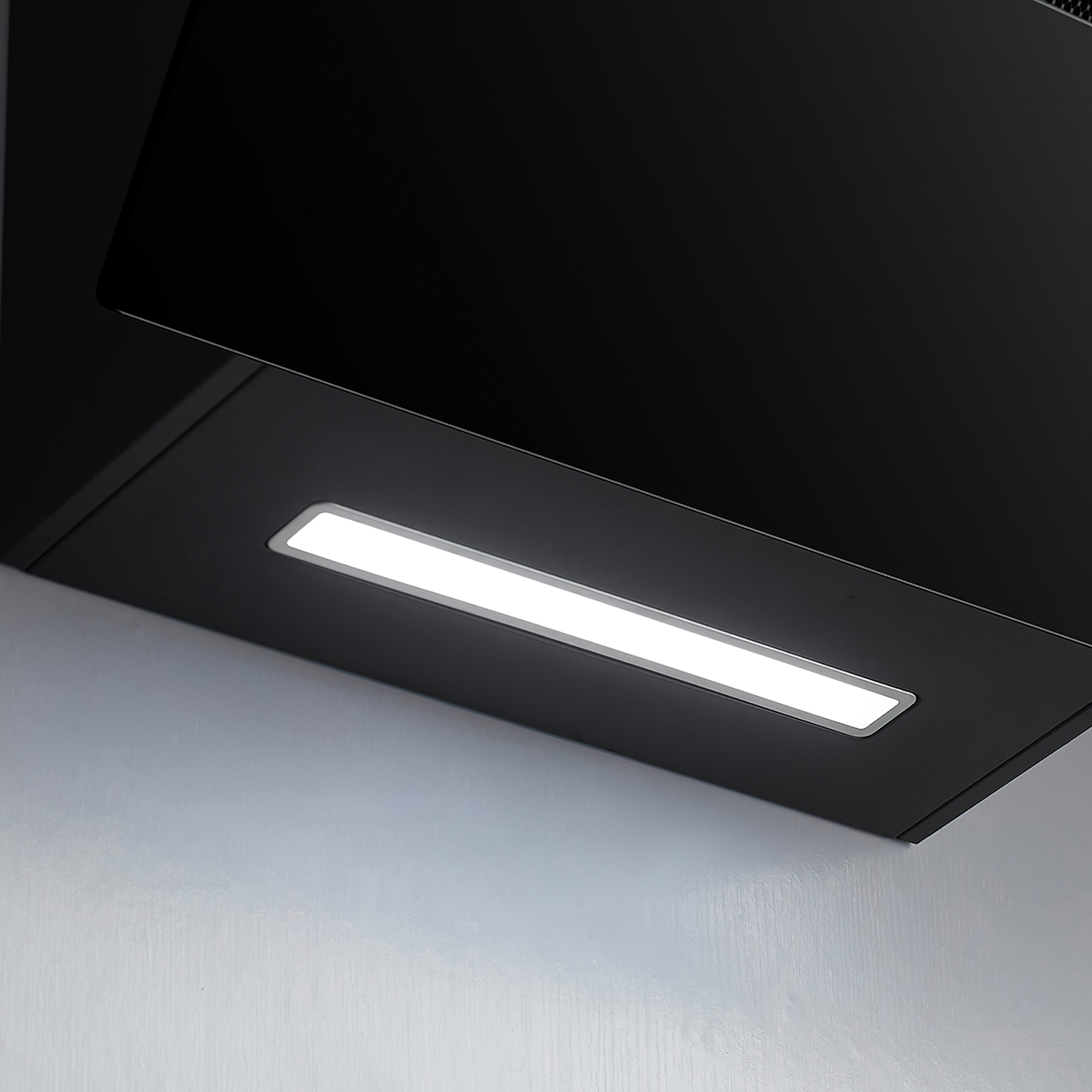 Eine schwarze Dunstabzugshaube mit hellem Licht, das die Unterseite vor weißem Hintergrund beleuchtet.