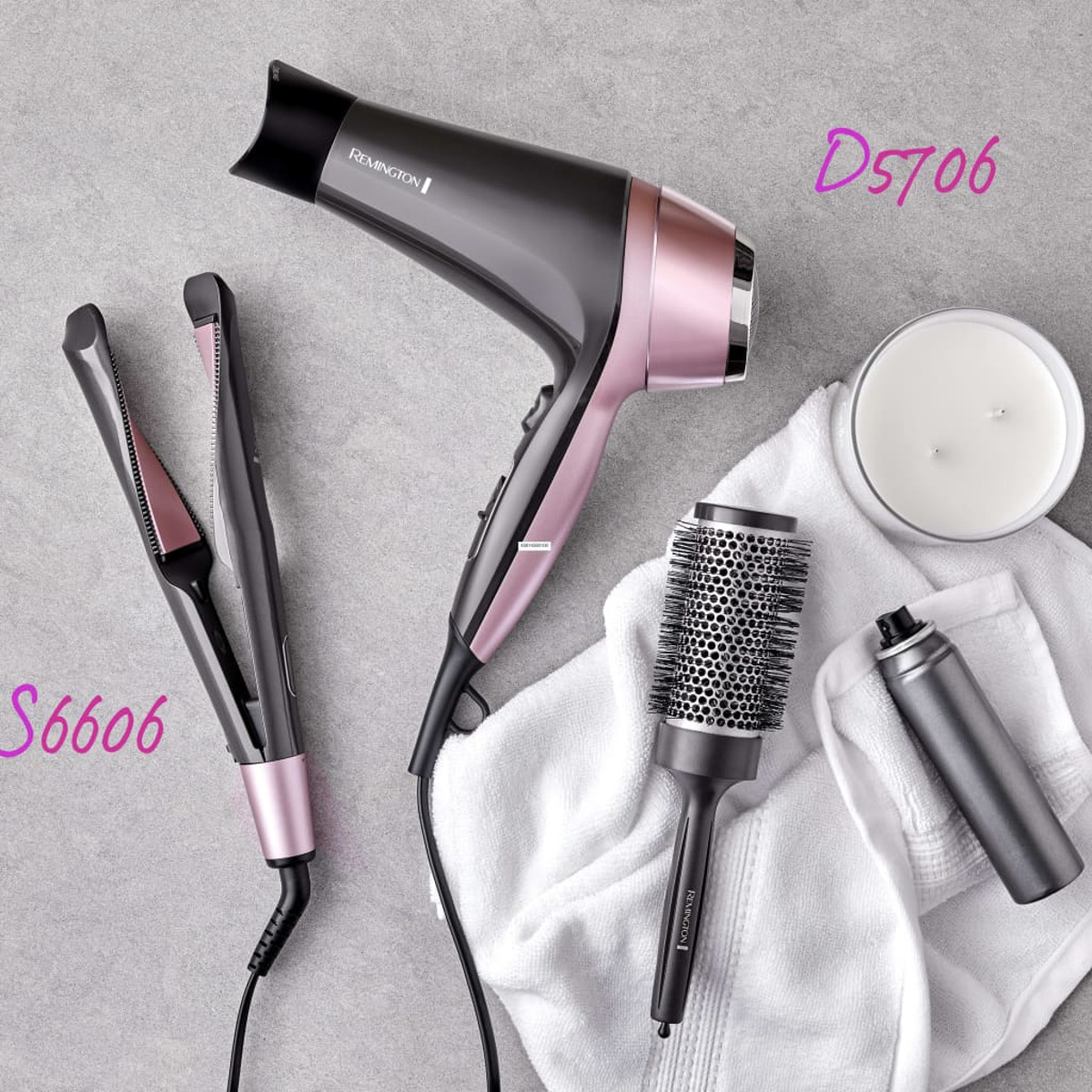 Narzędzia do stylizacji włosów: suszarka, prostownica, szczotka i spray. Wszystko różowe i szare.