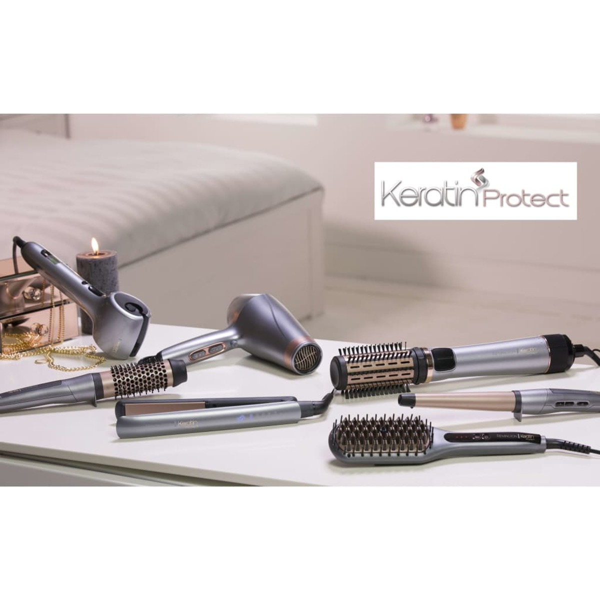 Verschiedene Haarstyling-Tools auf einer weißen Oberfläche. Ein Keratin Protect-Logo ist im Hintergrund sichtbar.