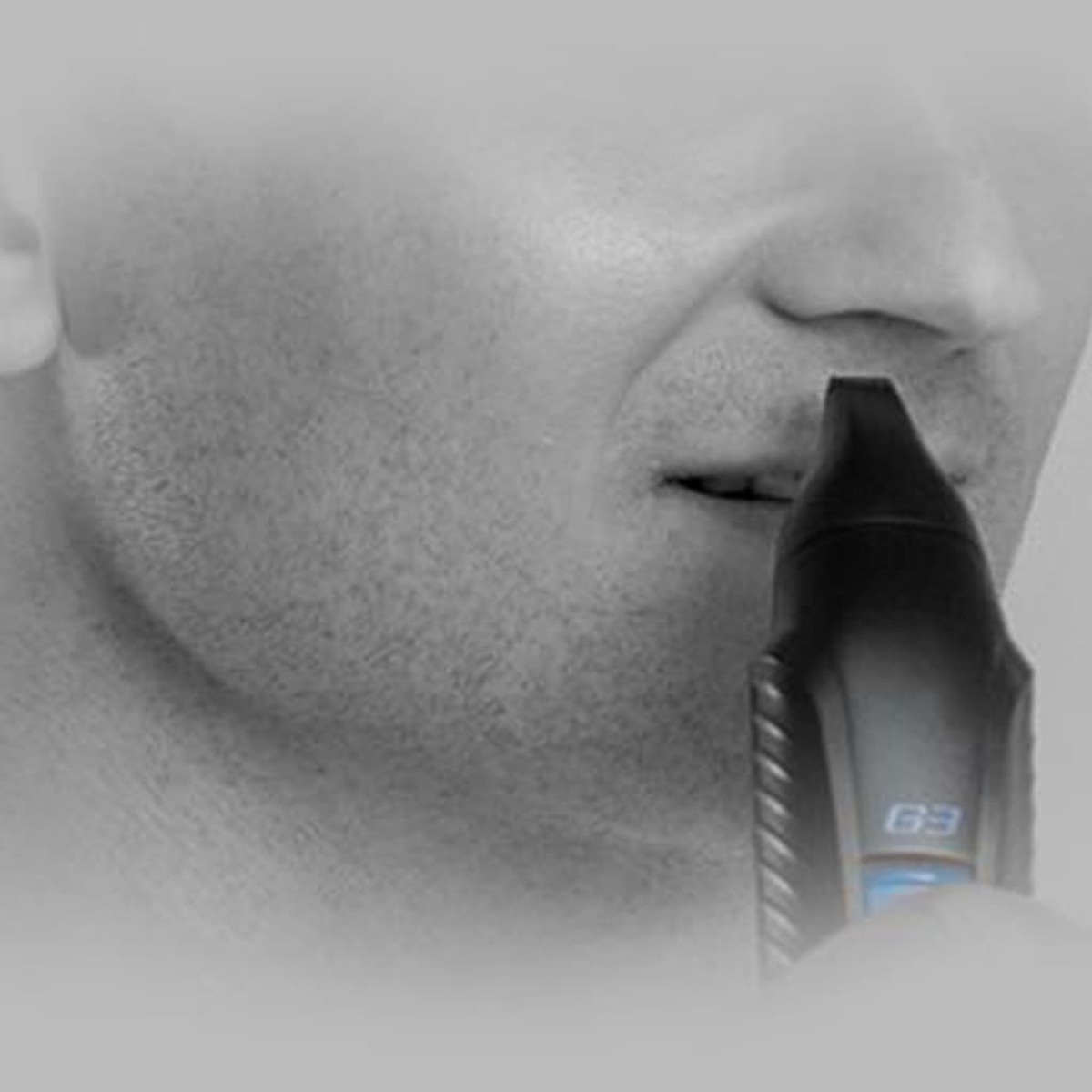 Un hombre usando un recortador de vello nasal. El recortador es negro y el hombre es de piel clara.
