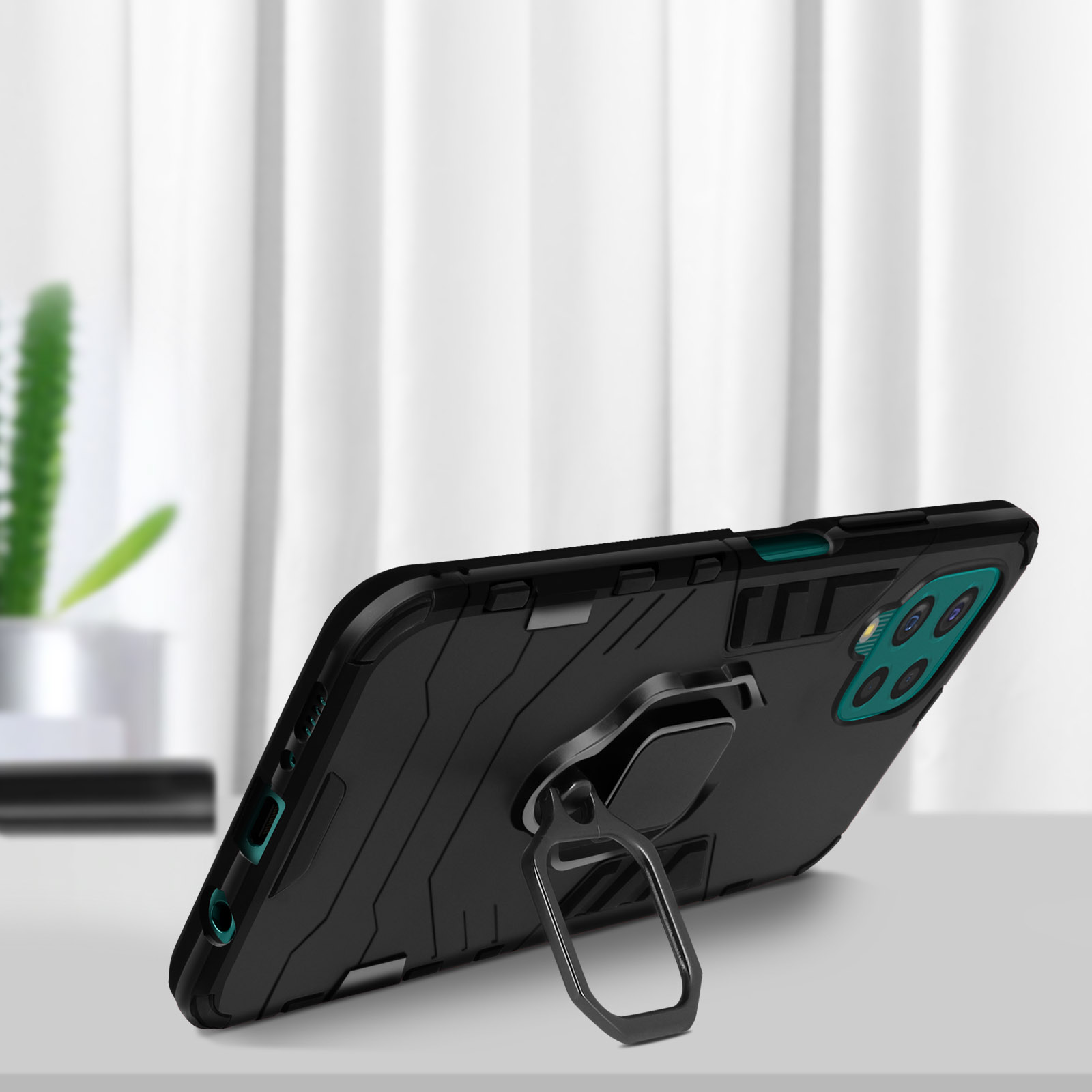 Una custodia per telefono nera con un supporto ad anello è su un tavolo. Lo sfondo è un muro bianco sfocato.