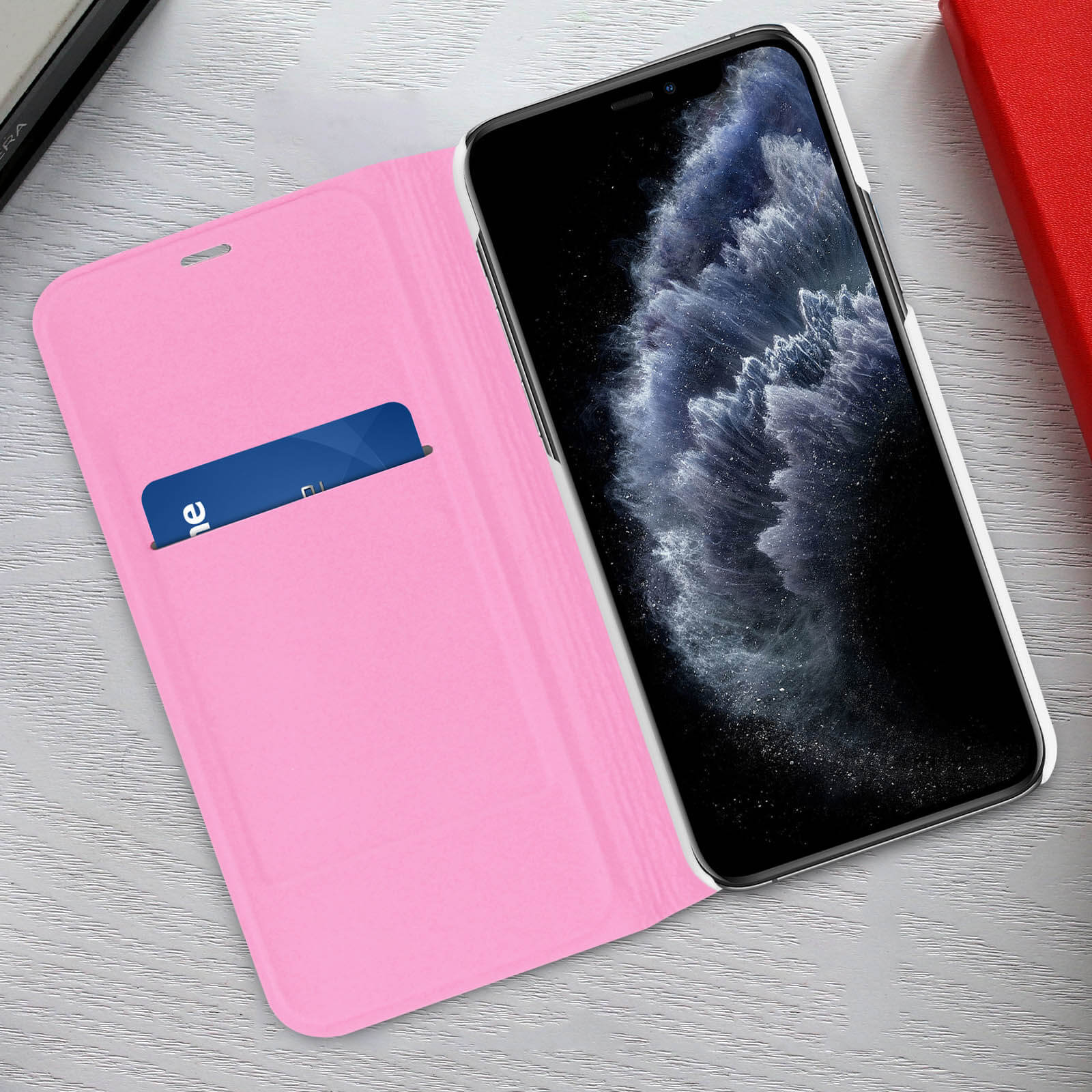 Custodia rosa aperta, rivelando telefono e tasca per carte. Il telefono è nero.