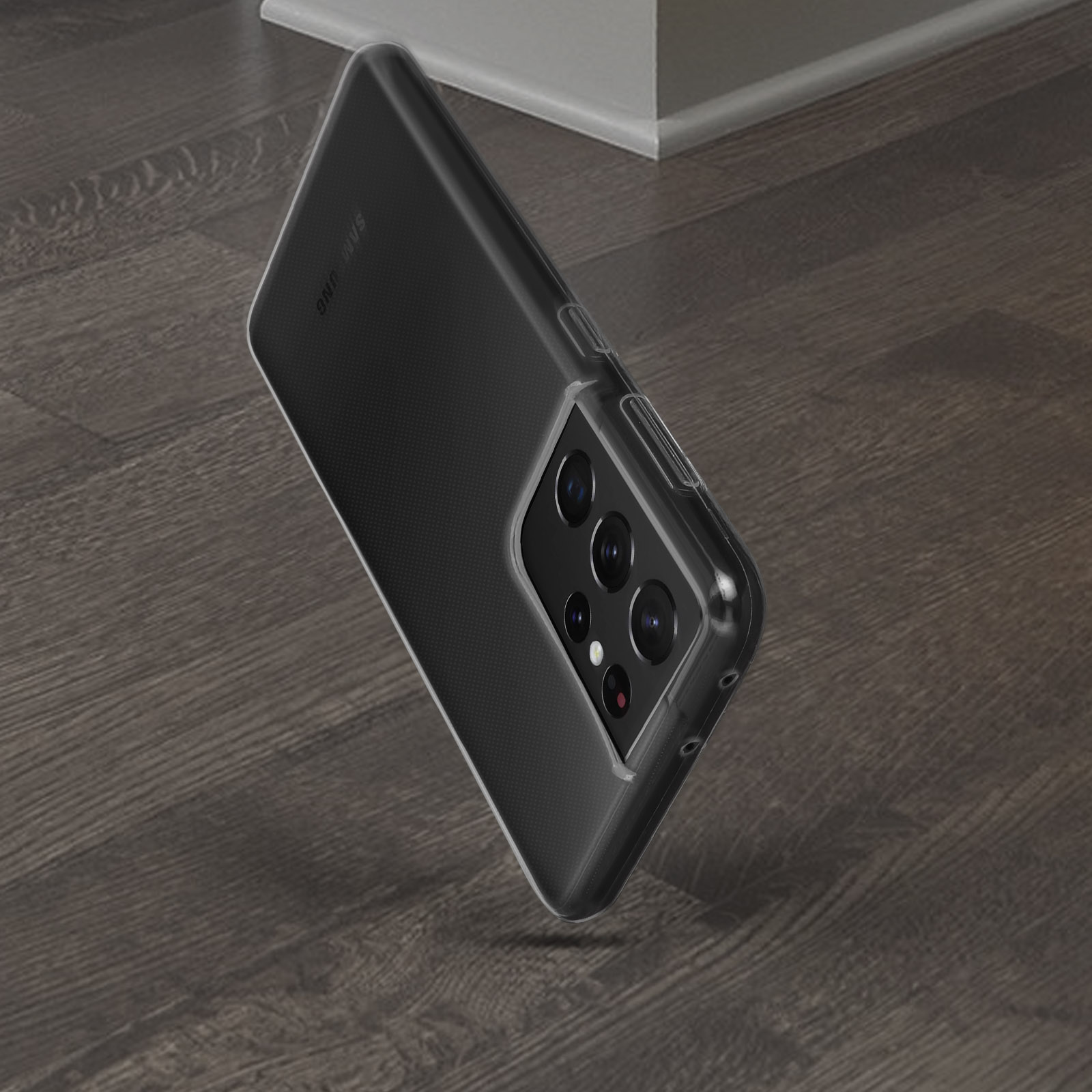 Un telefono in una custodia trasparente appoggiato su un pavimento di legno. Il telefono ha più fotocamere sul retro.