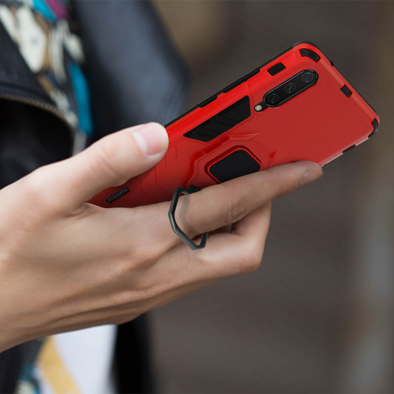 Una persona che tiene una custodia per telefono rossa con un supporto ad anello nero.