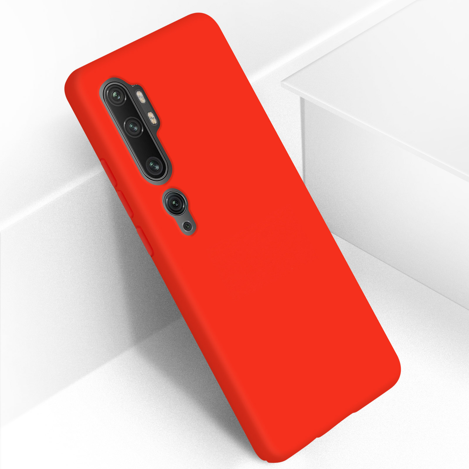 Smartphone rosso su superficie bianca angolata, con più fotocamere, sfondo bianco.
