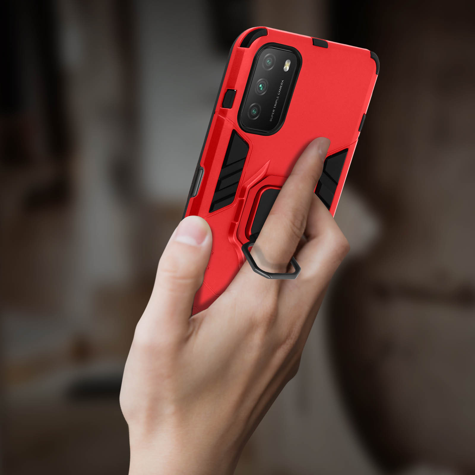 Eine Hand, die eine rote Handyhülle mit einem schwarzen Ringhalter hält. Die Handyhülle bedeckt das Telefon.