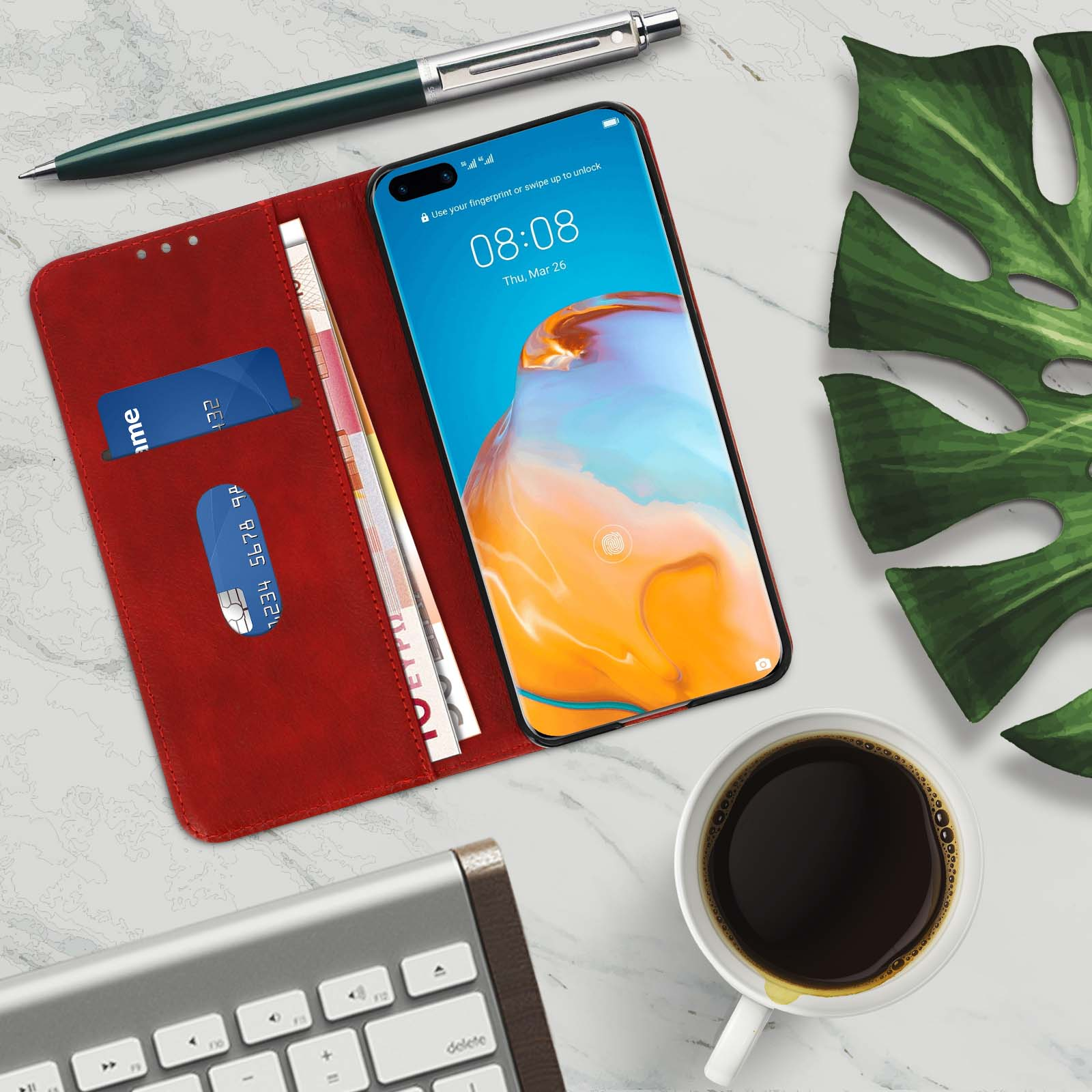 Un telefono e accessori su una superficie di marmo. Sono presenti una tazza di caffè, una tastiera e una penna.