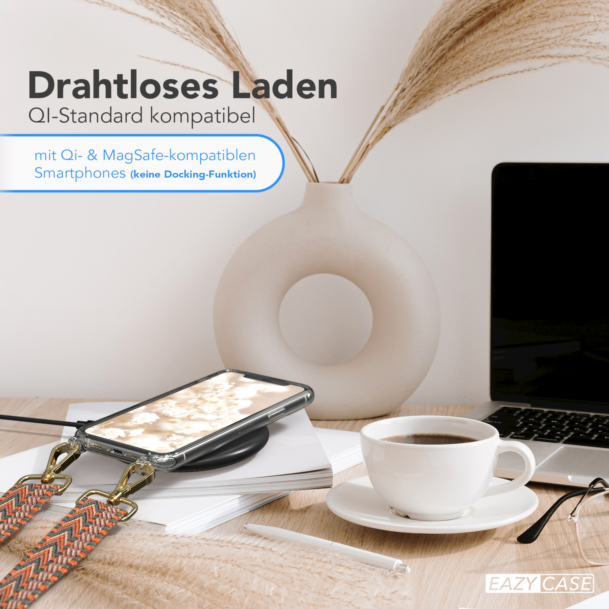 Telefon mit Hülle auf kabellosem Ladegerät, Kaffee, Laptop und Vase mit Pflanzen auf einem Holztisch.