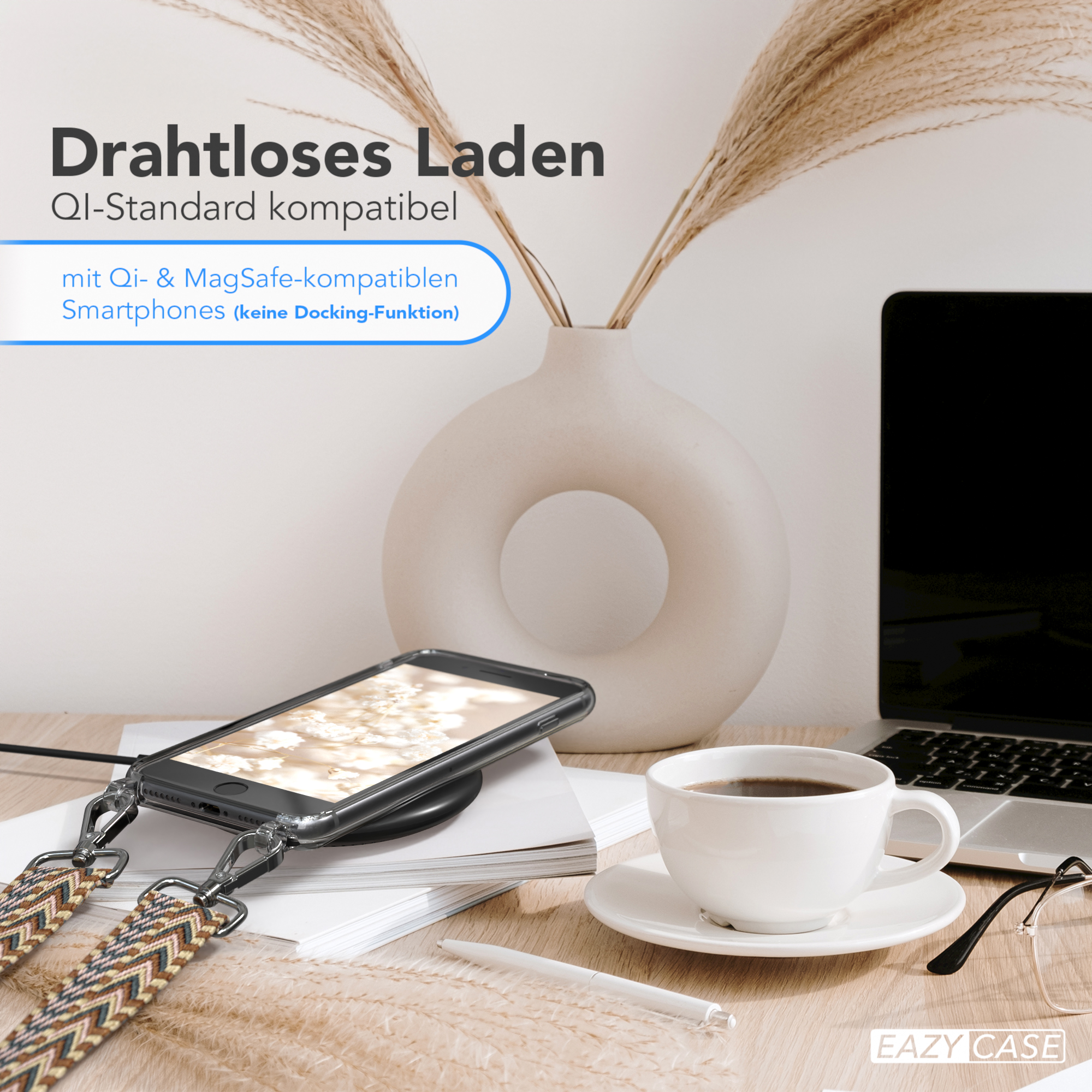 Telefon auf kabellosem Ladegerät mit Riemen, Kaffeetasse und Laptop auf einem Tisch.