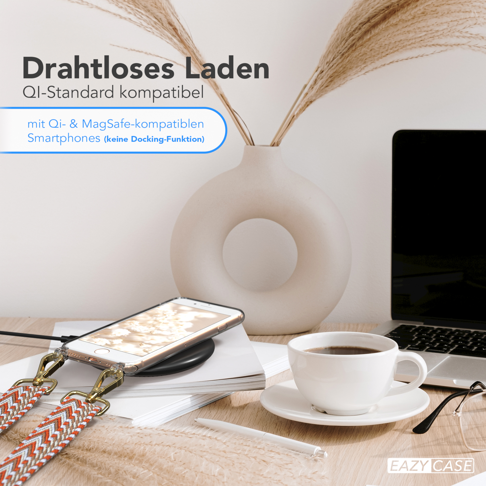 Telefon auf Ladegerät, Kaffeetasse, Laptop und Vase mit Pflanzen auf dem Holztisch.