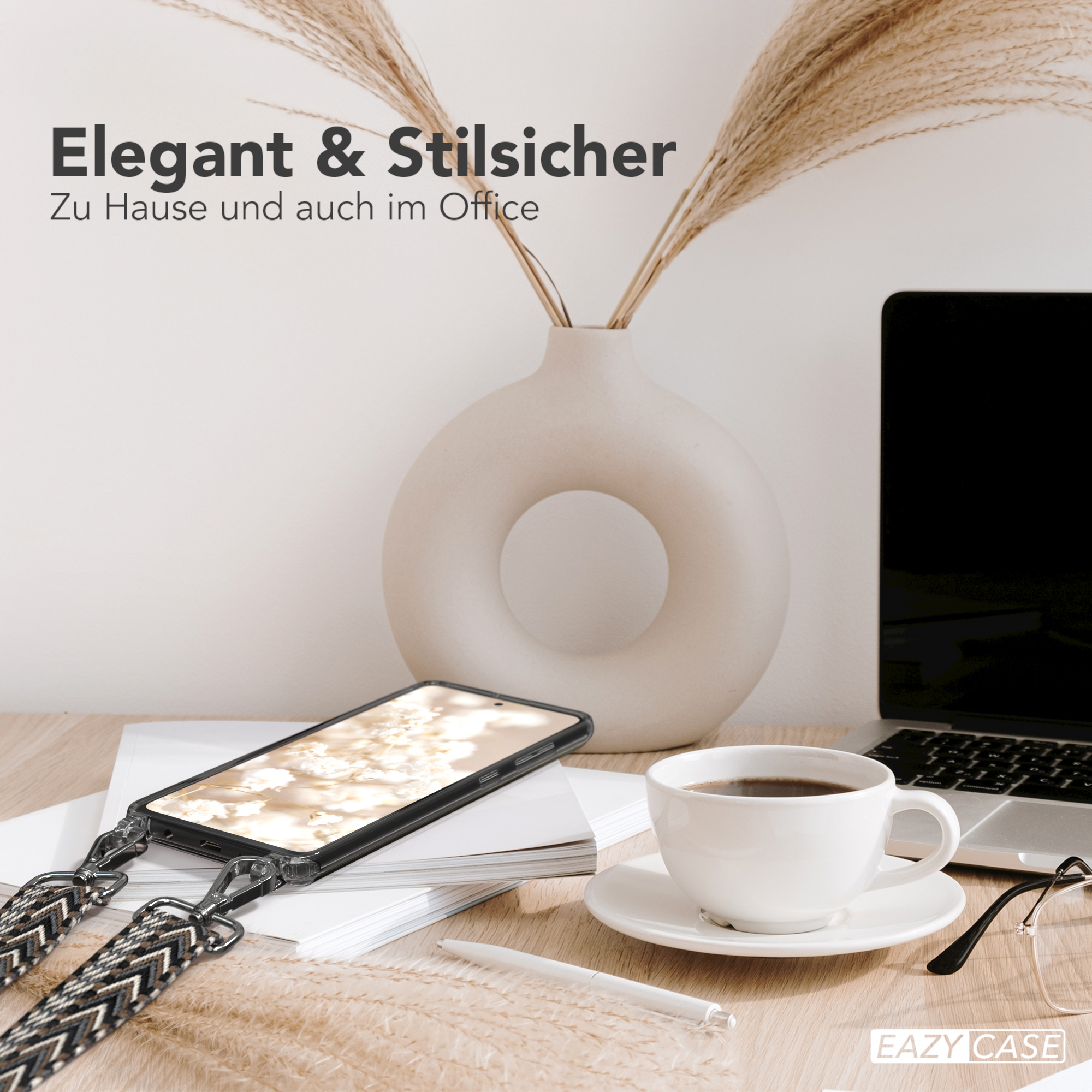 Telefon in einer Hülle mit Trageriemen, auf einem Schreibtisch mit Tasse, Blumen und Laptop.