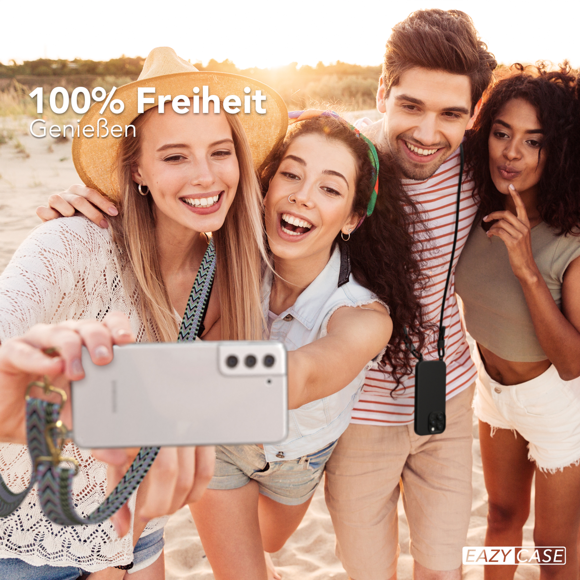 Vier Personen machen ein Selfie. Sie lächeln und sind am Strand. Telefon mit Riemen ist sichtbar. Sonniger Tag.