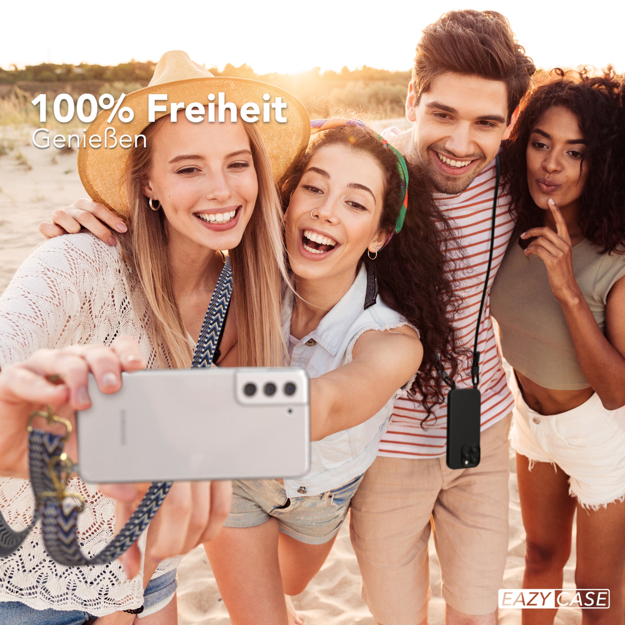 Vier lächelnde Personen machen ein Selfie am Strand, sonniger Tag.