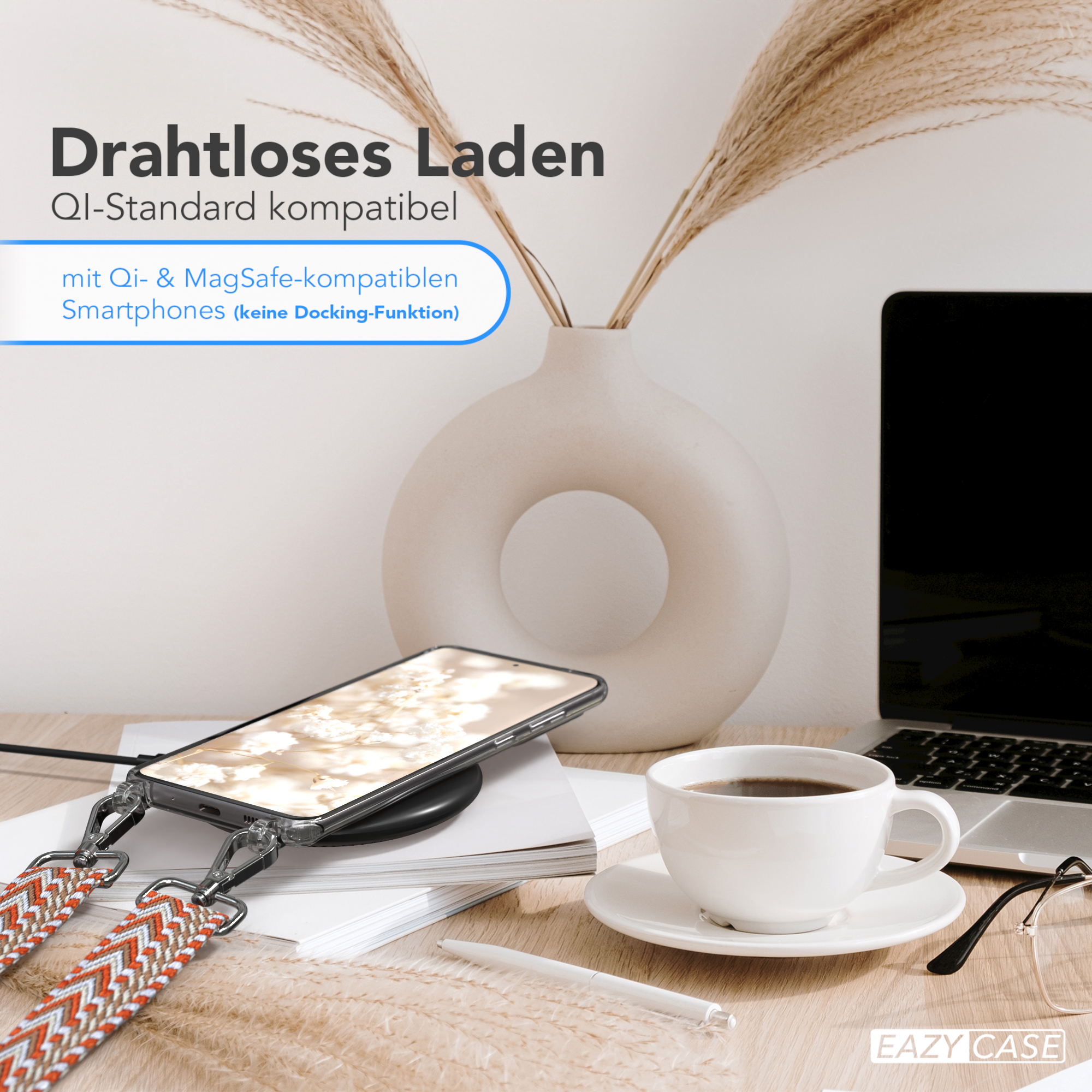 Telefon mit Hülle auf kabellosem Ladegerät, Kaffee, Laptop und Vase mit Pflanzen auf einem Holztisch.