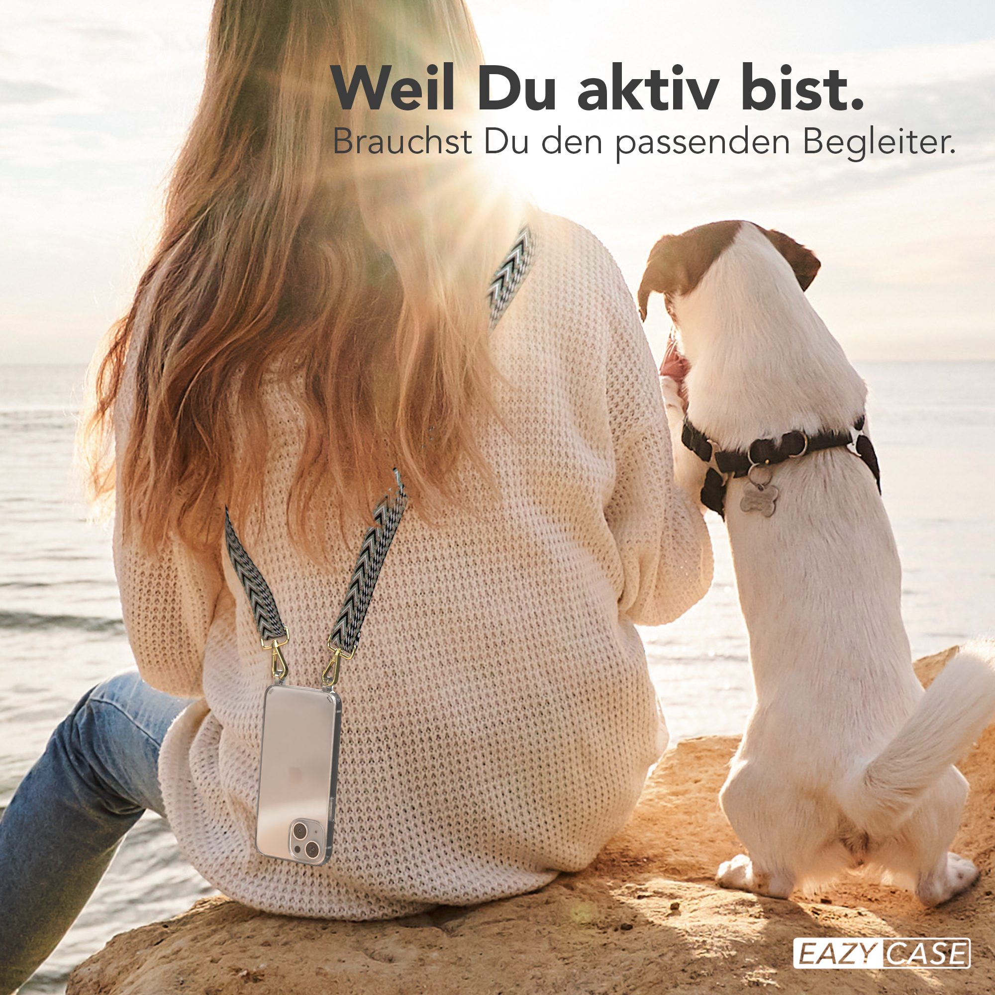 Frau am Strand mit Handyhülle und Hund. Die Hülle hat einen Gurt. Der Hund ist weiß.