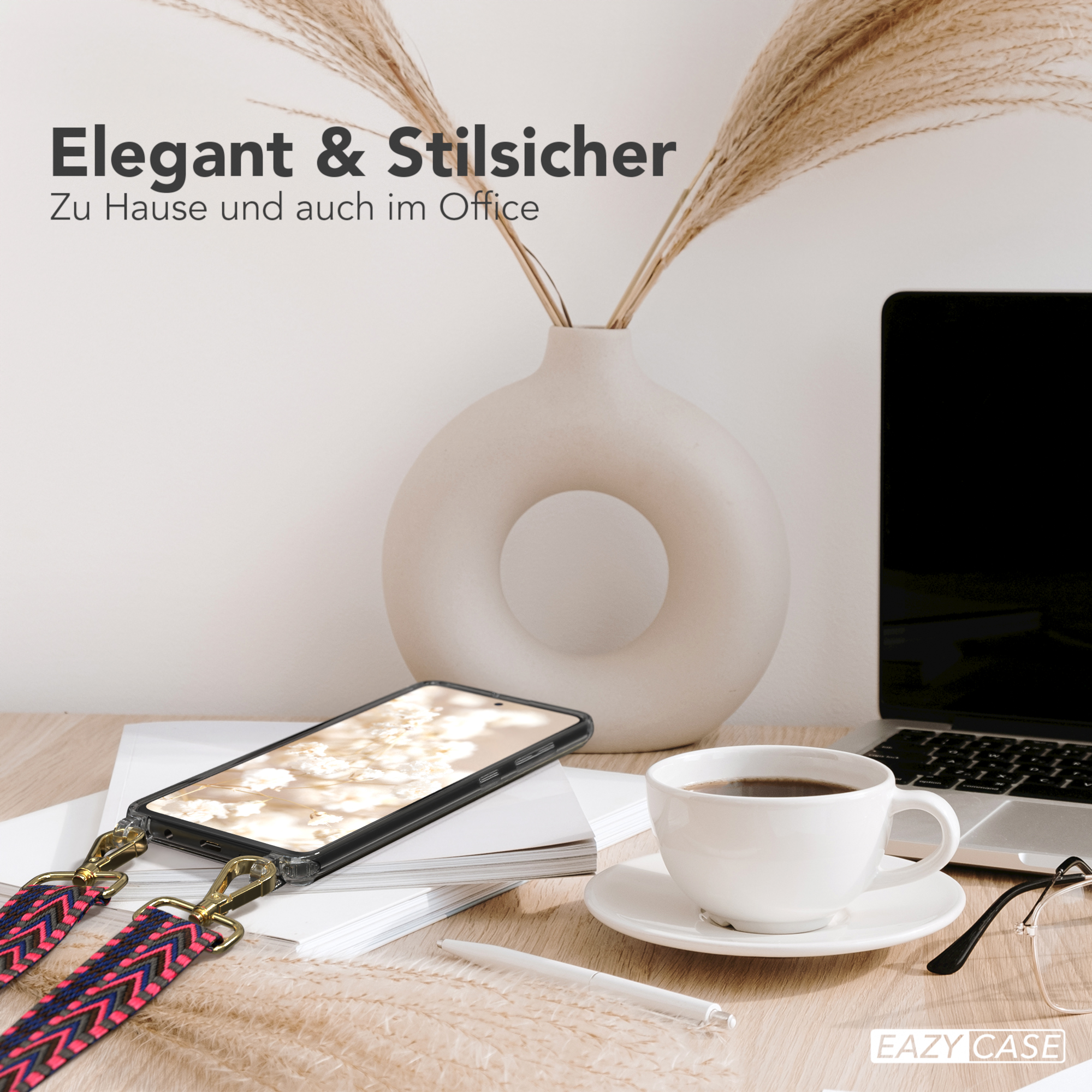 Ein Telefon mit Riemen liegt auf einem Schreibtisch mit Laptop, Kaffee und Blumen. Elegante Büroeinrichtung.