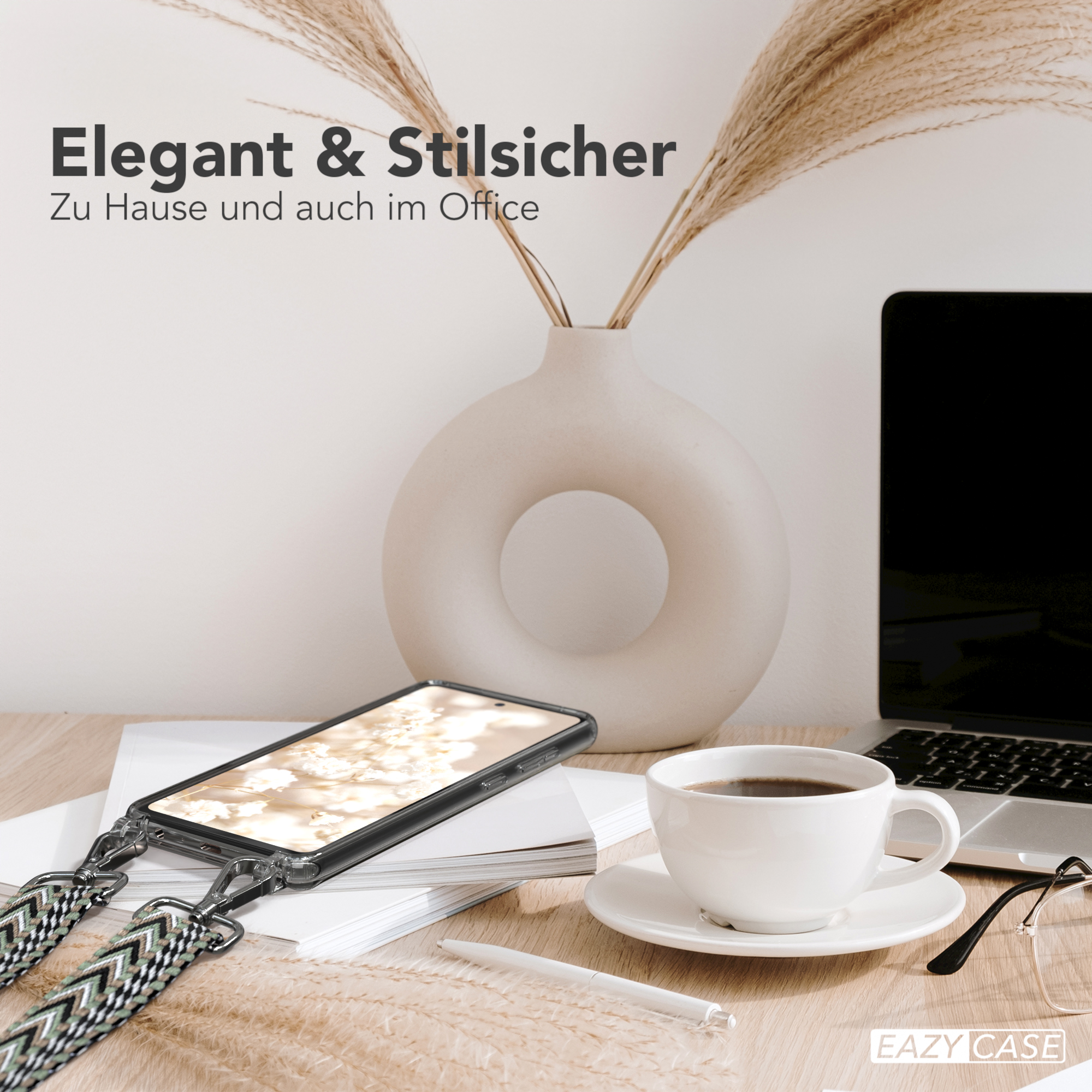 Telefon auf Ladegerät, Kaffeetasse, Vase mit Pflanzen und Laptop auf dem Schreibtisch.