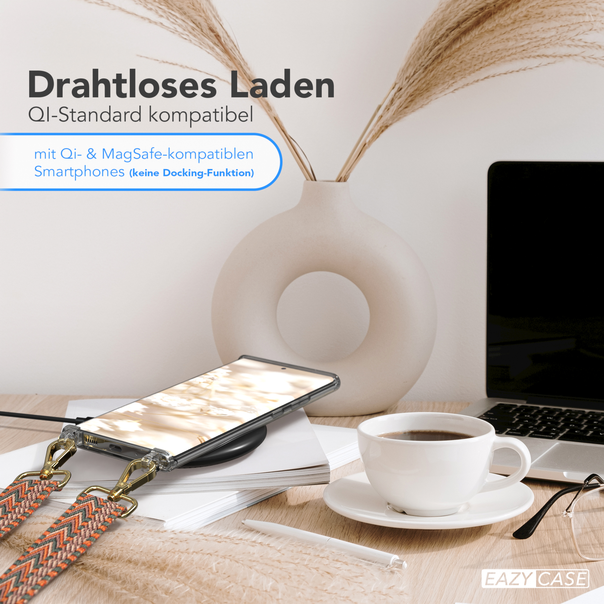 Telefon auf kabellosem Ladegerät, Kaffee, Vase mit Pflanzen und ein Laptop auf dem Schreibtisch.