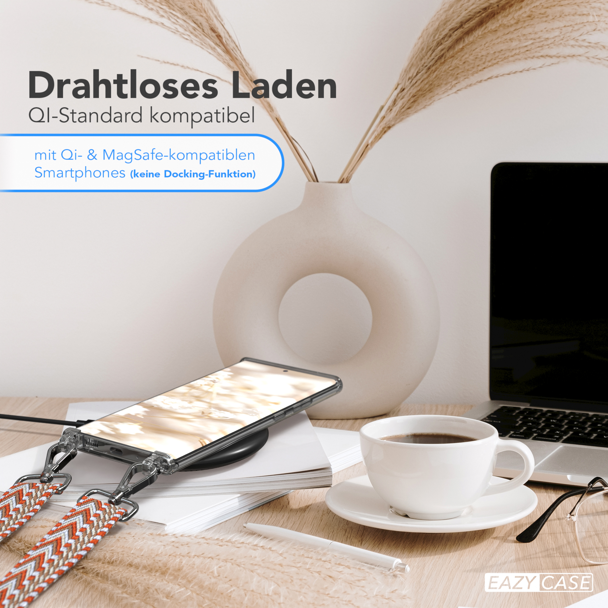 Ein Telefon auf einem kabellosen Ladegerät mit farbenfrohem Armband, neben einer Kaffeetasse und einem Laptop.