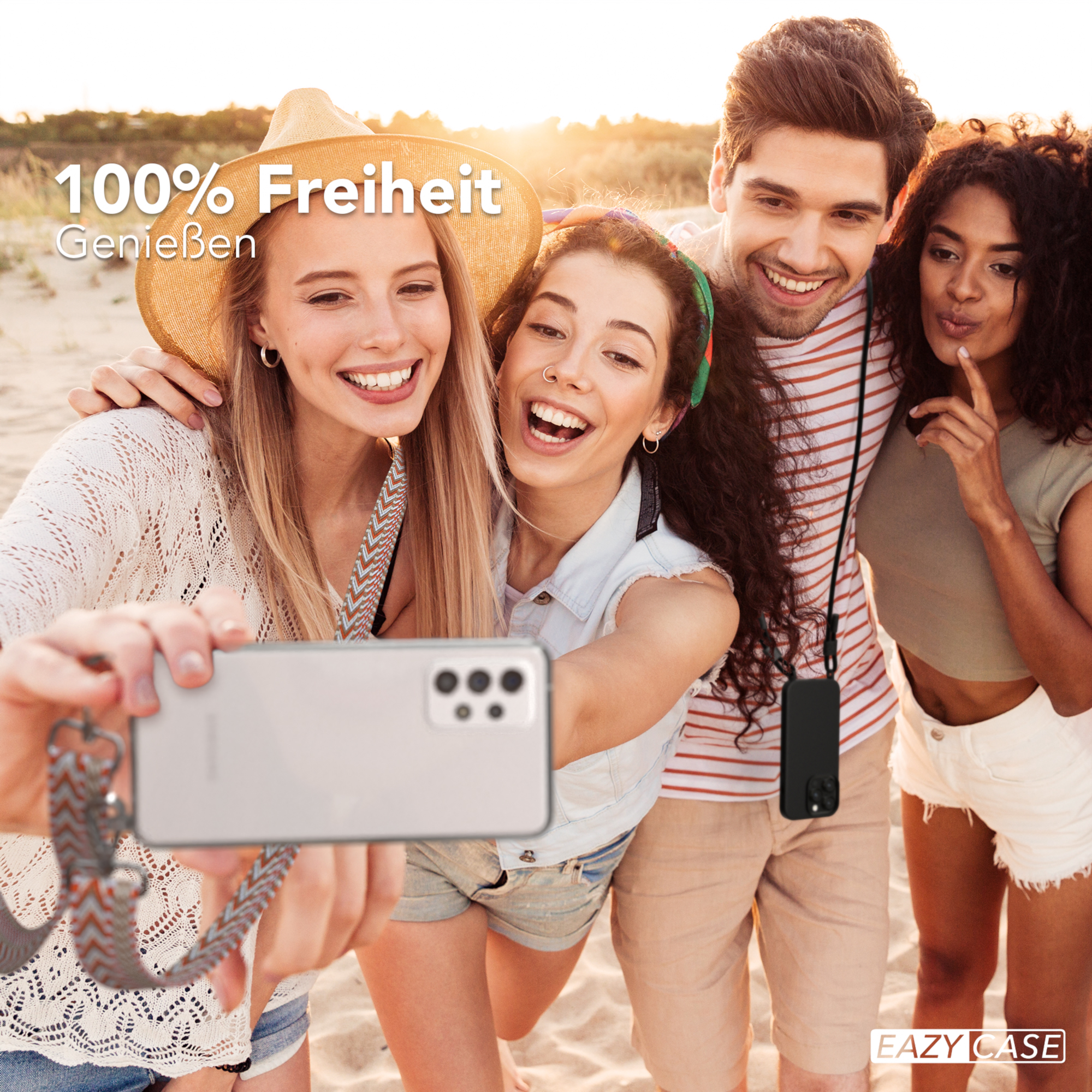 Vier Freunde machen ein Selfie am Strand. Einer hält ein Telefon. Strand im Hintergrund.