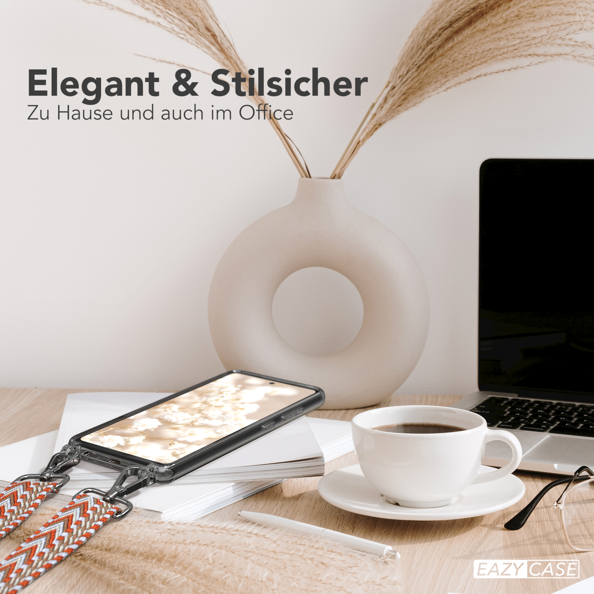 Ein Telefon mit einem Riemen auf einem Schreibtisch, mit einer Tasse Kaffee, Laptop und Brille.