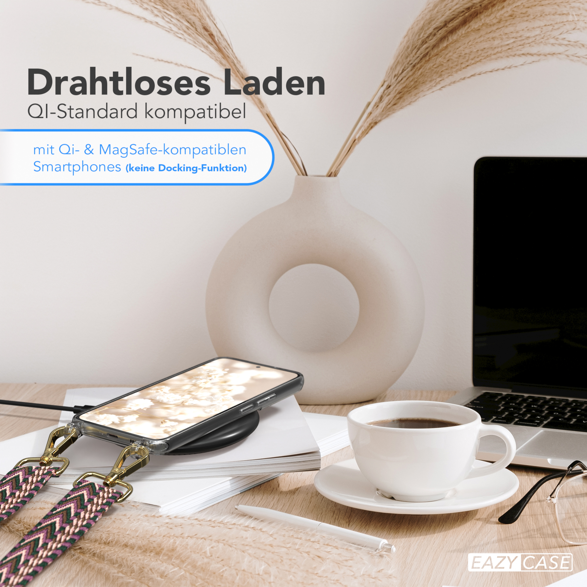 Ein Telefon auf einem kabellosen Ladegerät, Kaffee und ein Laptop auf einem Schreibtisch mit einer Vase im Hintergrund.