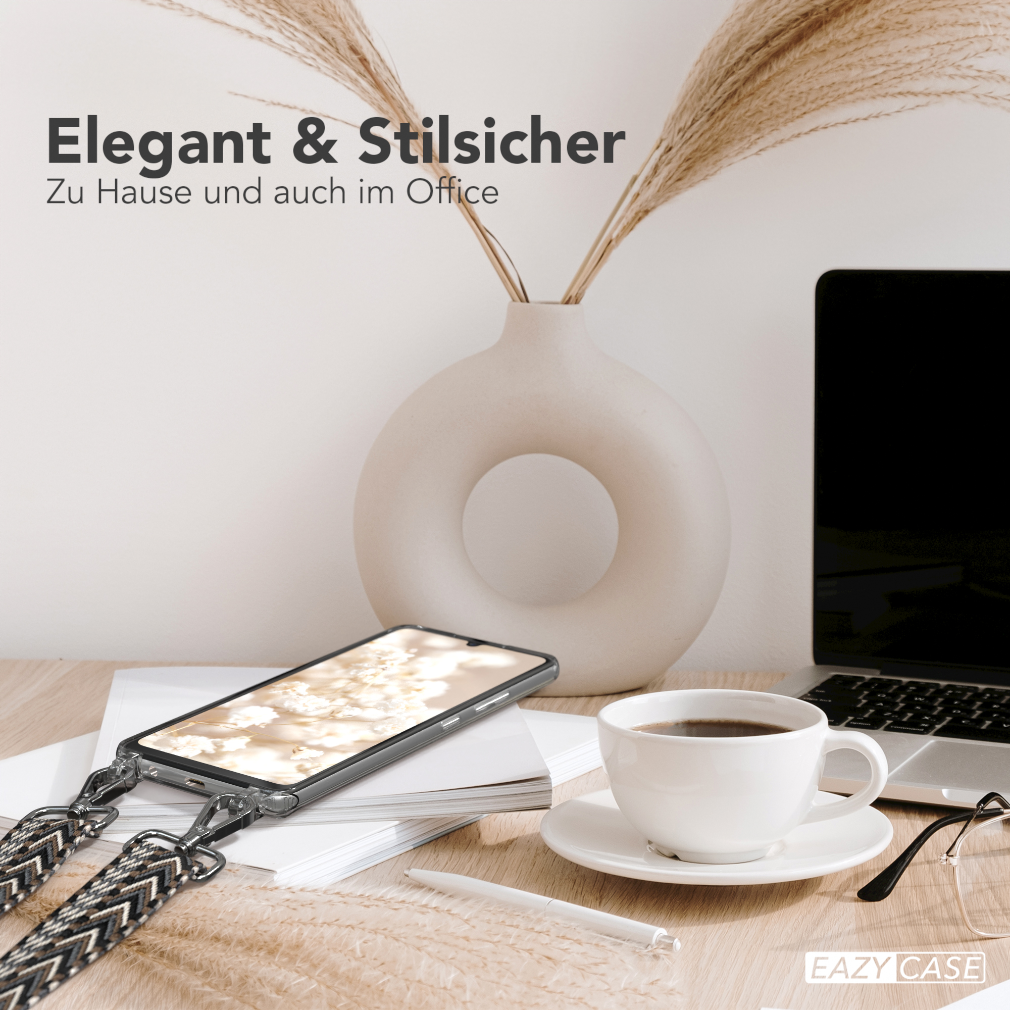 Ein Telefon mit Riemen liegt auf einem Schreibtisch mit Kaffeetasse und Laptop.
