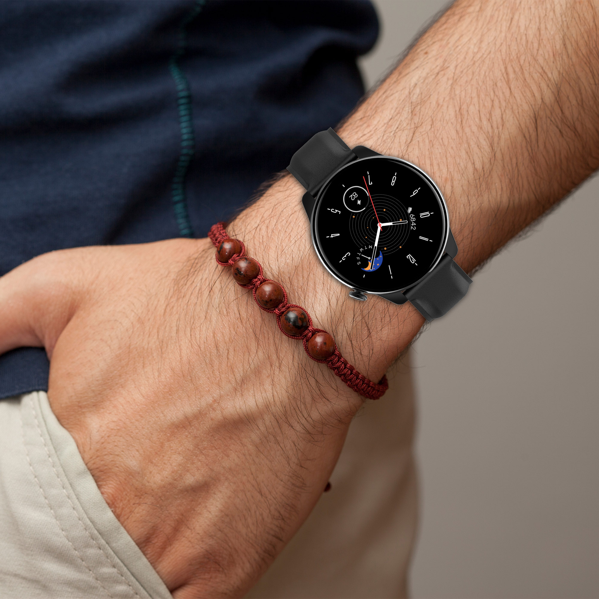 Das Handgelenk eines Mannes mit Smartwatch und Armband. Das Zifferblatt ist schwarz.