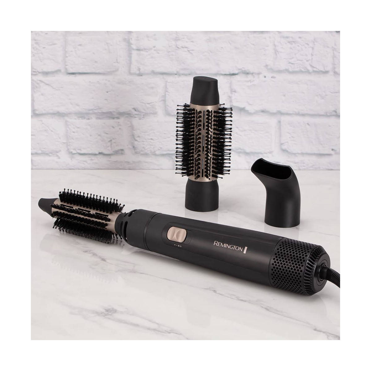 Un moldeador de cabello Remington negro y plateado con tres accesorios. Los accesorios son cepillos.