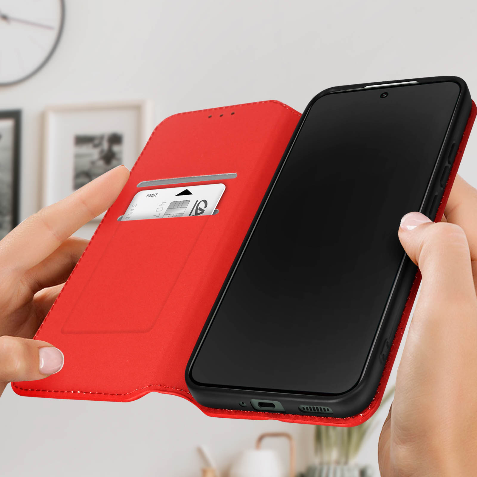 Le mani tengono aperta una custodia rossa, rivelando un telefono nero e uno slot per schede con una carta.