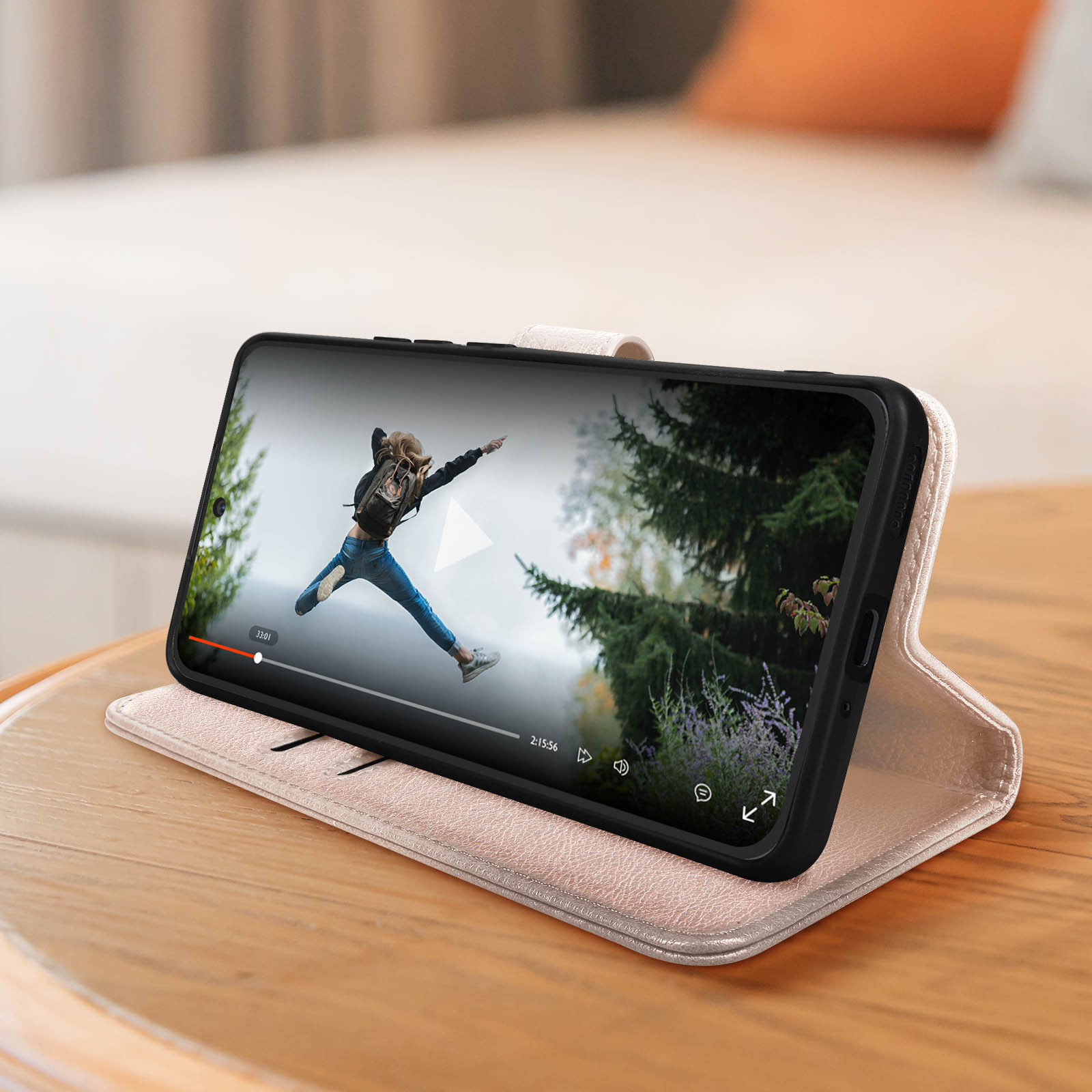 Smartphone dans un étui rose, ouvert pour montrer une vidéo. La scène représente une personne sautant.