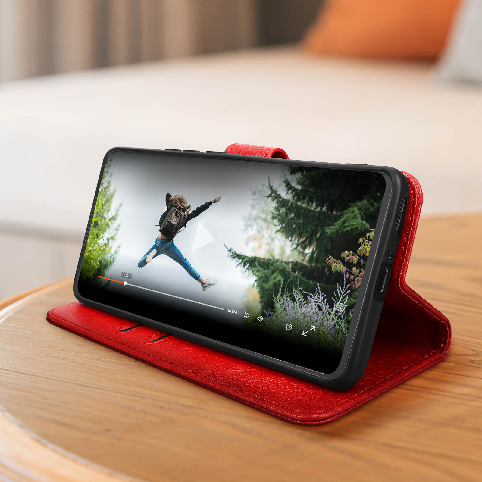 Ein Telefon mit rotem Case zeigt ein Video einer springenden Person.
