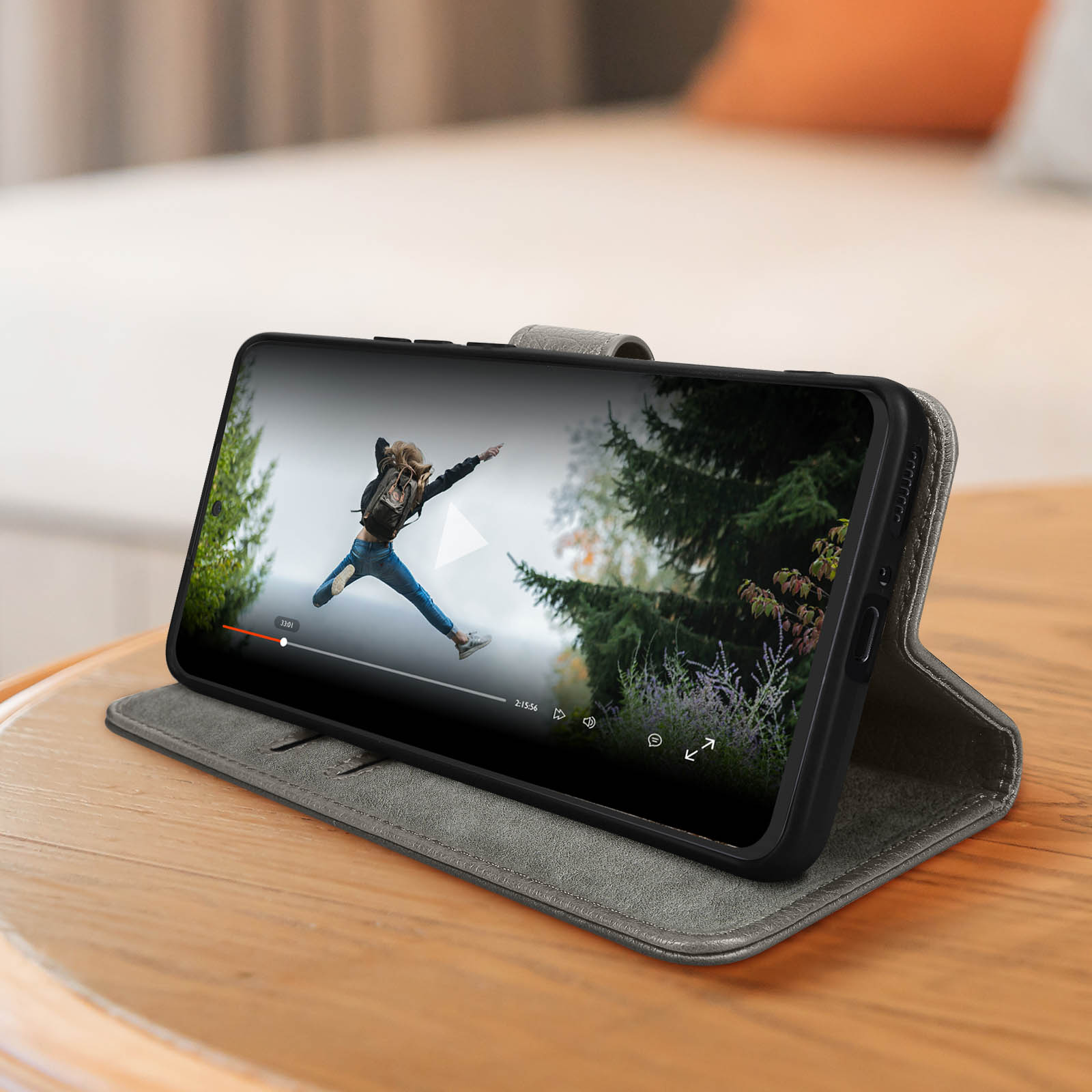 Téléphone dans un étui montrant une vidéo sur l'écran, posé sur une surface en bois.