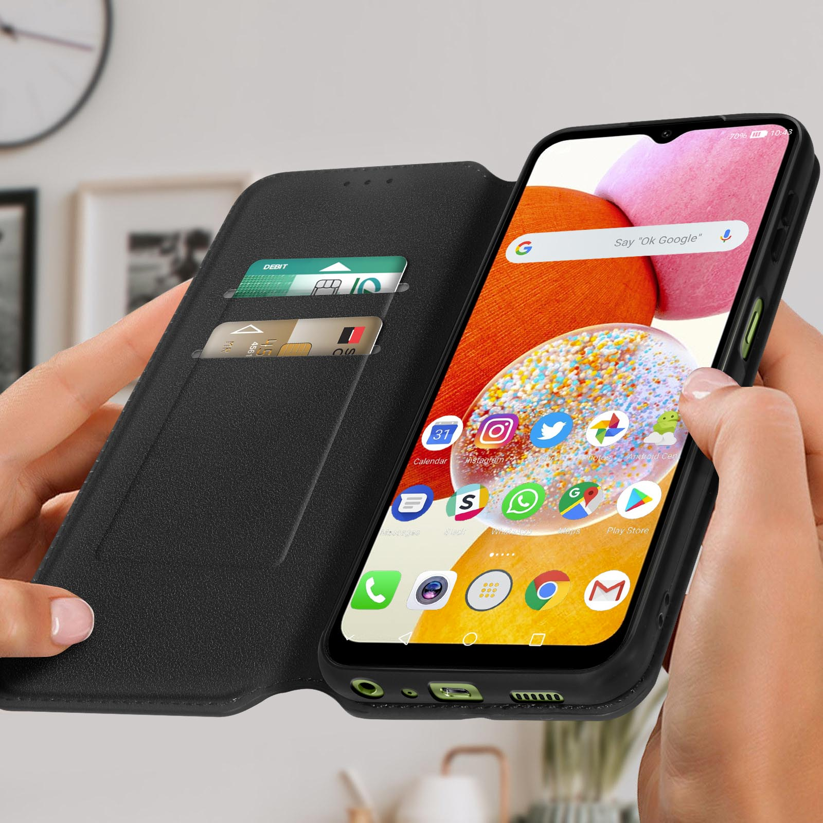 De handen van een persoon die een telefoonhoes vasthoudt met een telefoon erin. Het scherm van de telefoon toont apps.