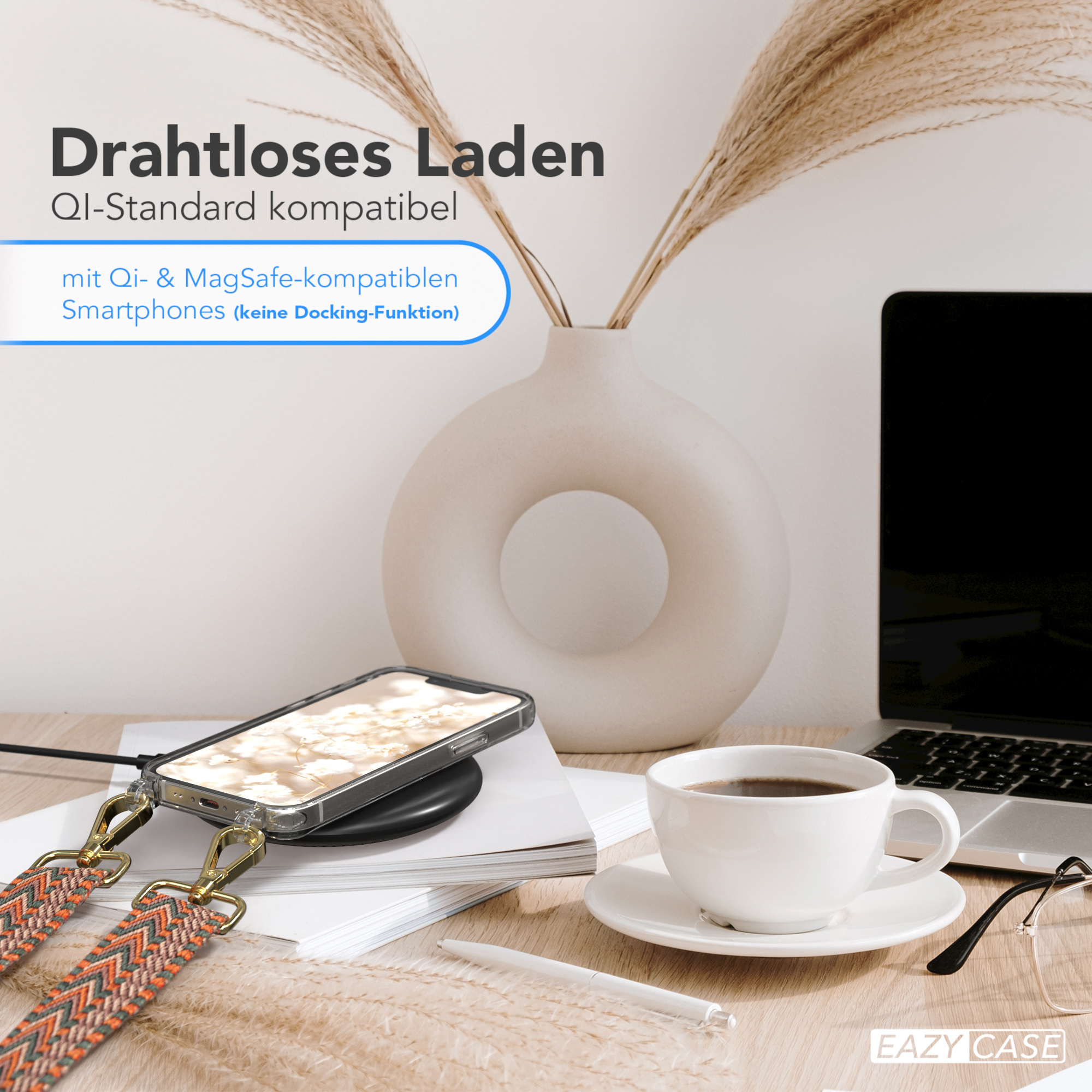 Telefon auf Ladegerät mit Kaffeetasse, Laptop und Dekopflanzen.
