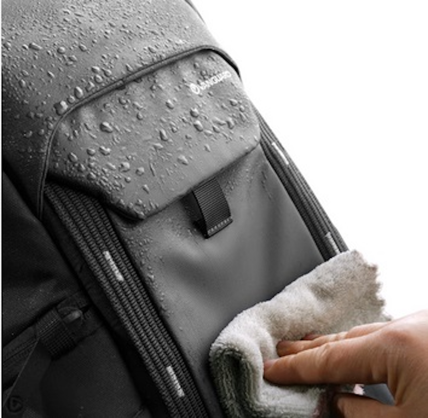 Schwarzer Rucksack mit Wassertropfen, der mit einem Tuch abgewischt wird.
