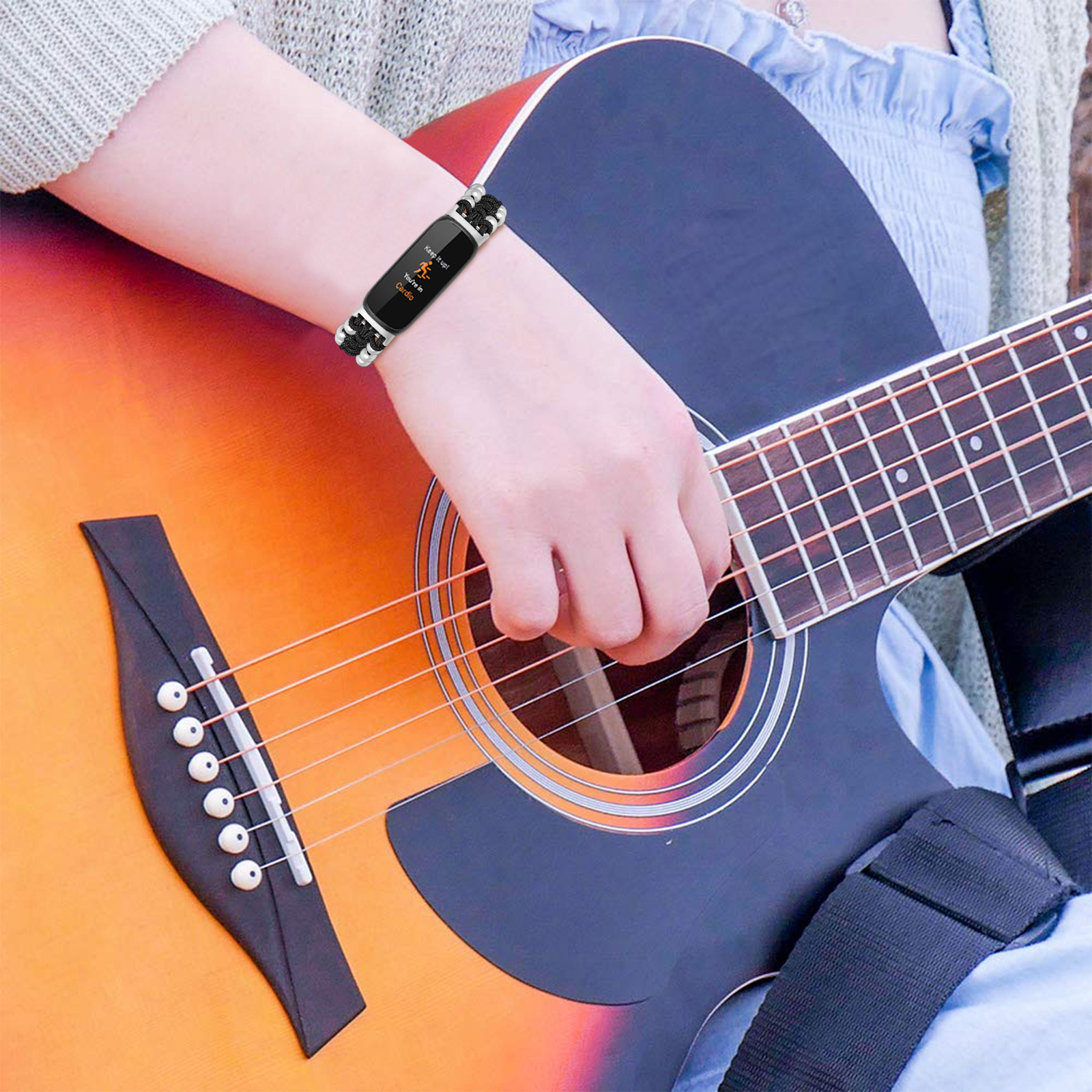 Person spielt Gitarre, trägt ein Armband mit einer Smartwatch.