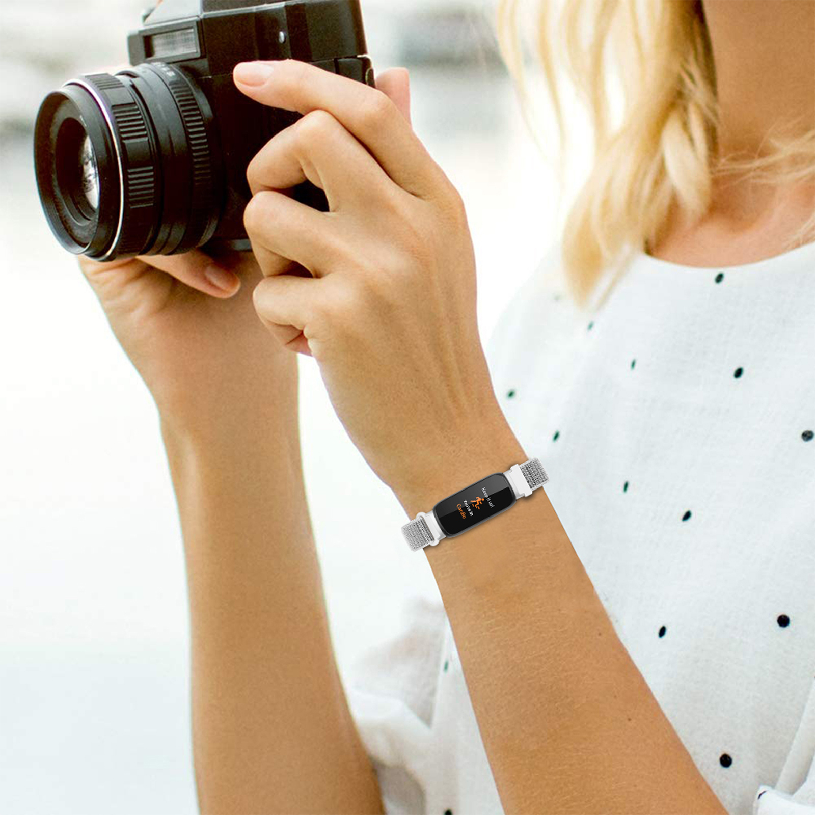 Eine Frau macht ein Foto mit einer Kamera und trägt ein Smart-Armband am Handgelenk.