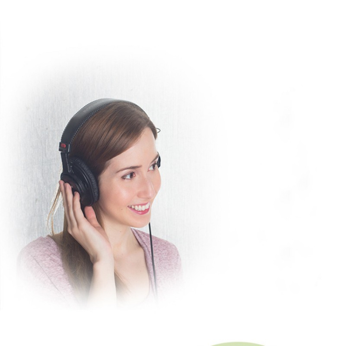 Eine Frau mit schwarzen Kopfhörern lächelt, während sie Musik hört. Der Hintergrund ist verschwommen weiß.