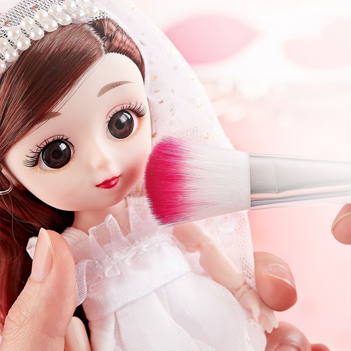 Ein Make-up-Pinsel trägt Rouge auf das Gesicht einer Puppe auf. Die Puppe trägt ein weißes Kleid.