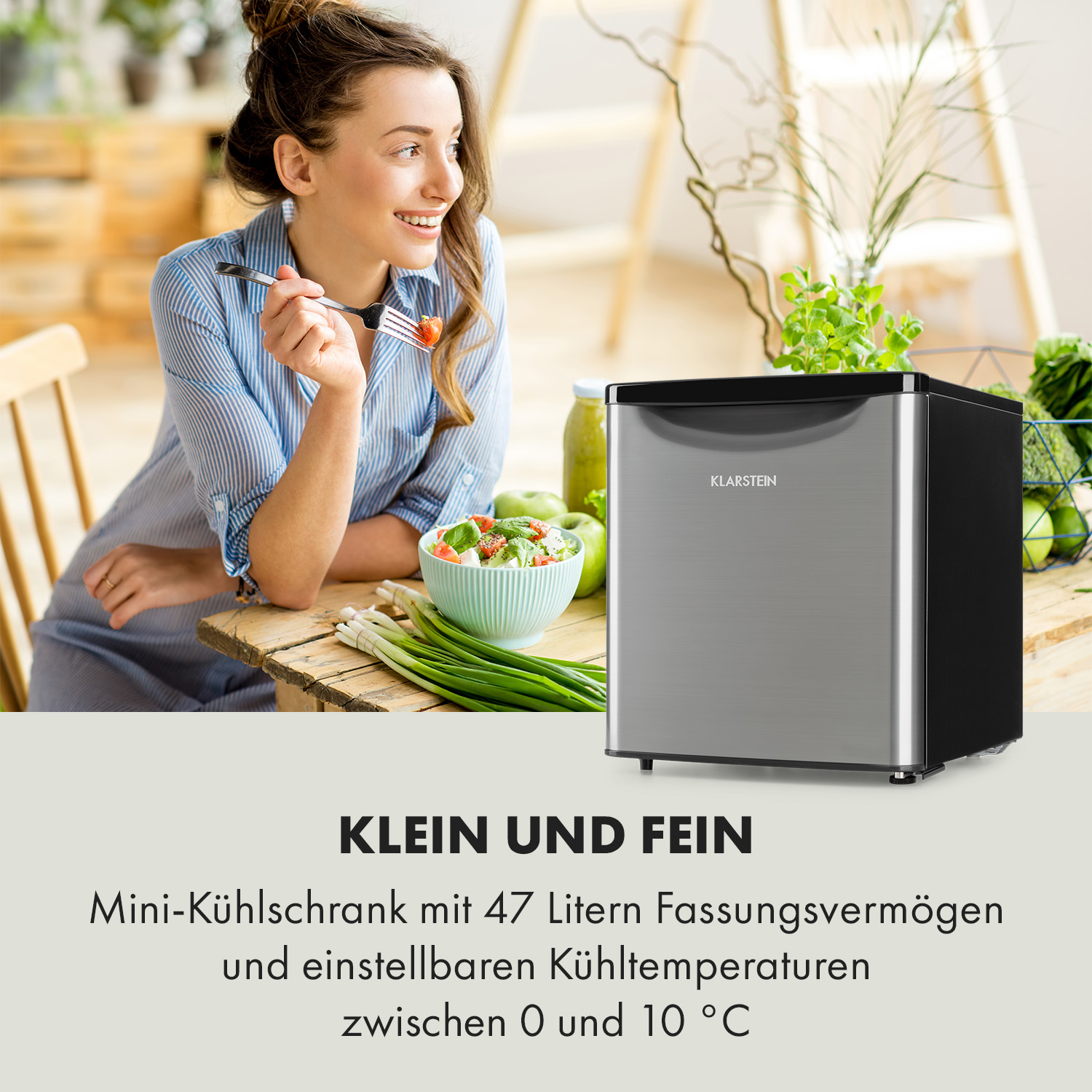 Eine Frau mit einem Mini-Kühlschrank, einem Tisch mit Essen und einer grünen Pflanze im Hintergrund.