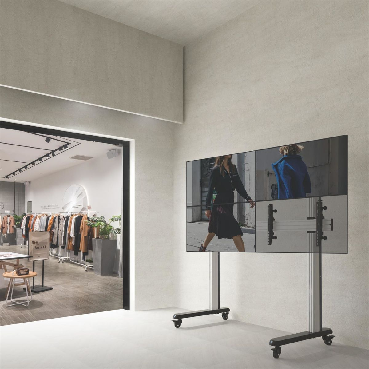 Escena interior. Pantalla con cuatro pantallas. Tienda de ropa al fondo.
