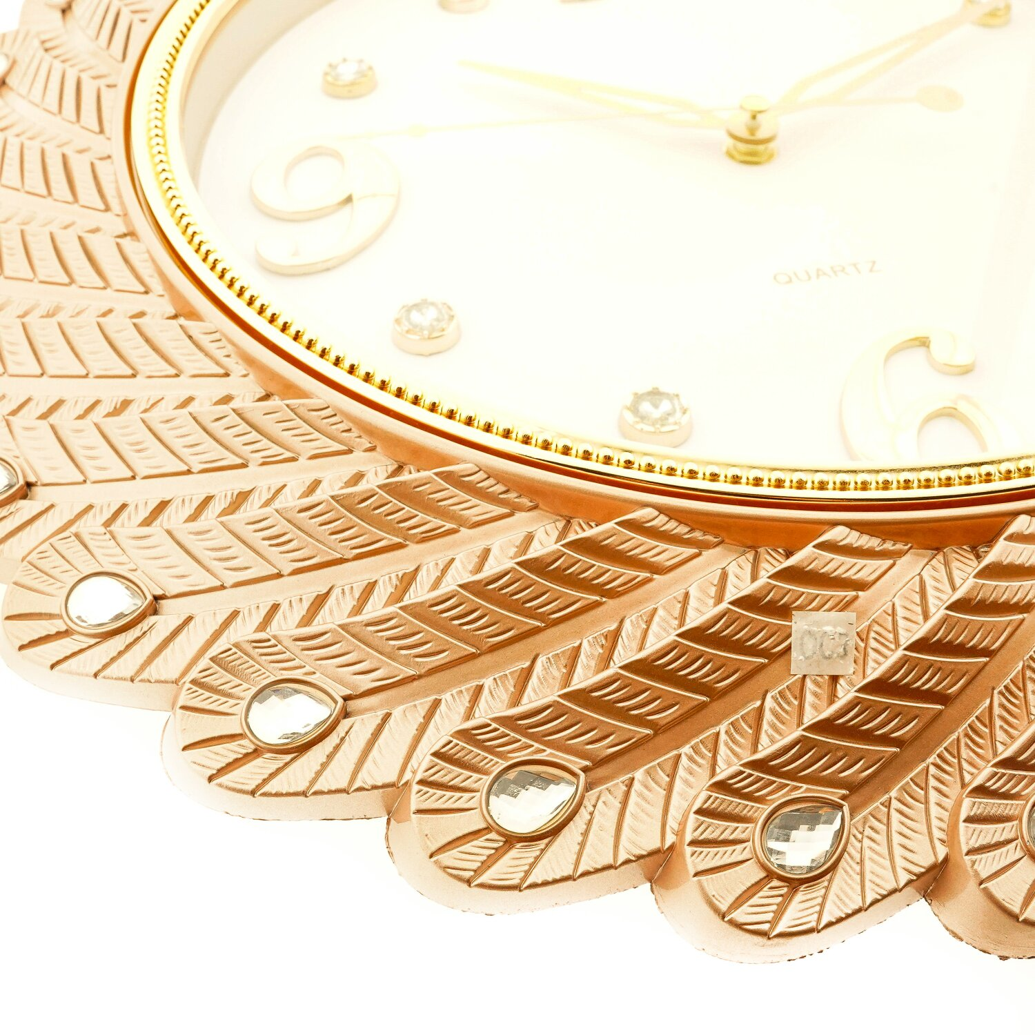 Nahaufnahme einer goldfarbenen Uhr. Sie hat ein Pfauenfedern-Design mit Kristallverzierungen.