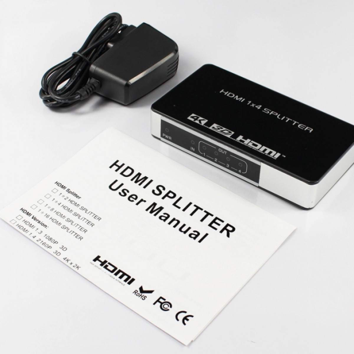 HDMI splitter with power adapter and user manual. Black and white color scheme.