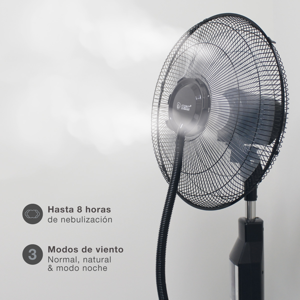 Un ventilador de pedestal negro. Tiene una jaula negra y está soplando niebla. El texto indica nebulización.