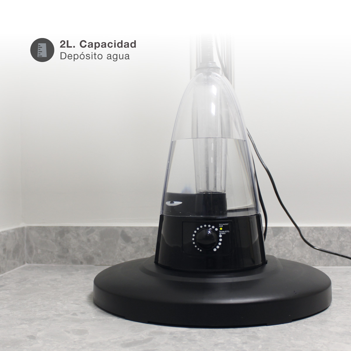 Un humidificador negro y transparente sobre una superficie gris, con una base negra. El depósito de agua es visible.
